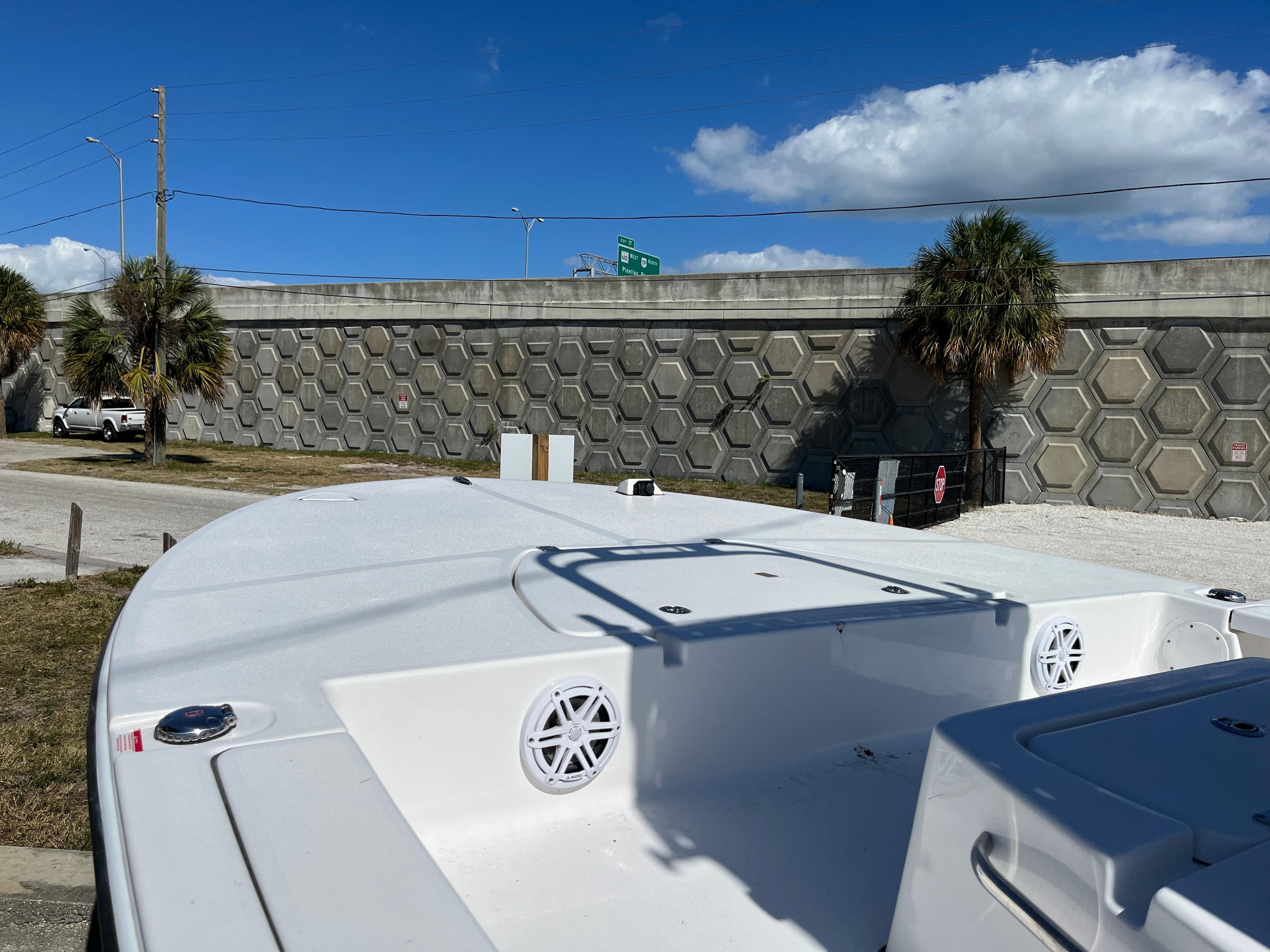 2025 Tidewater 25 TPC boat with white deck and speakers, parked near a concrete wall.