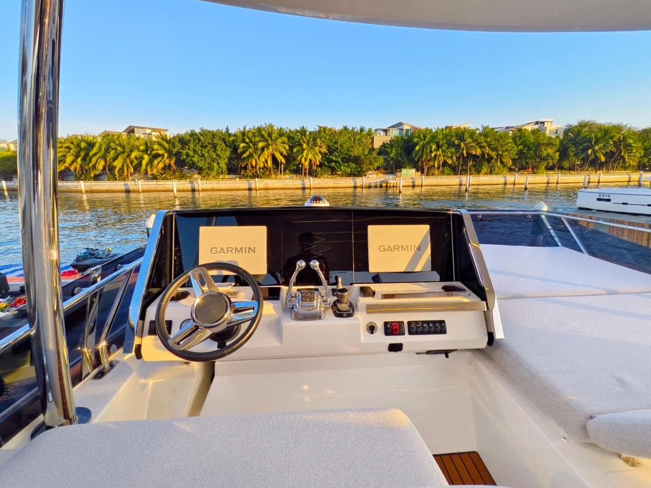 Prestige 590 yacht helm with Garmin displays, overlooking serene waterfront, 2022 model.