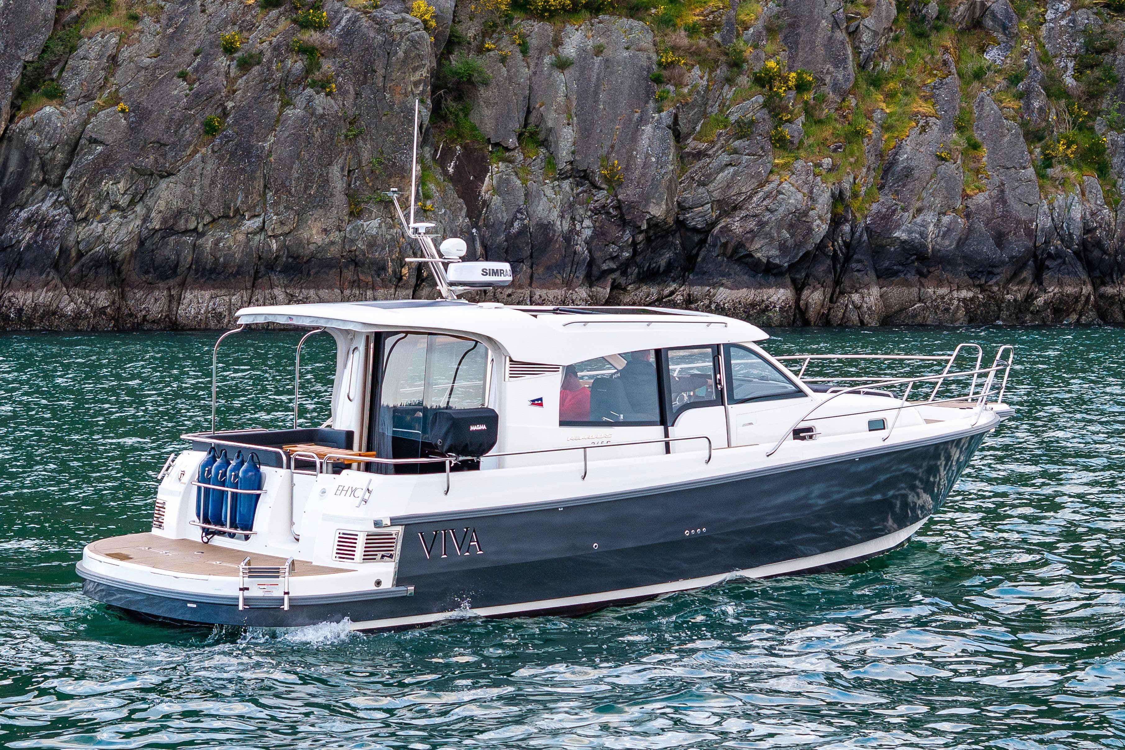 2022 Nimbus 365 Coupe boat cruising near rocky shoreline.