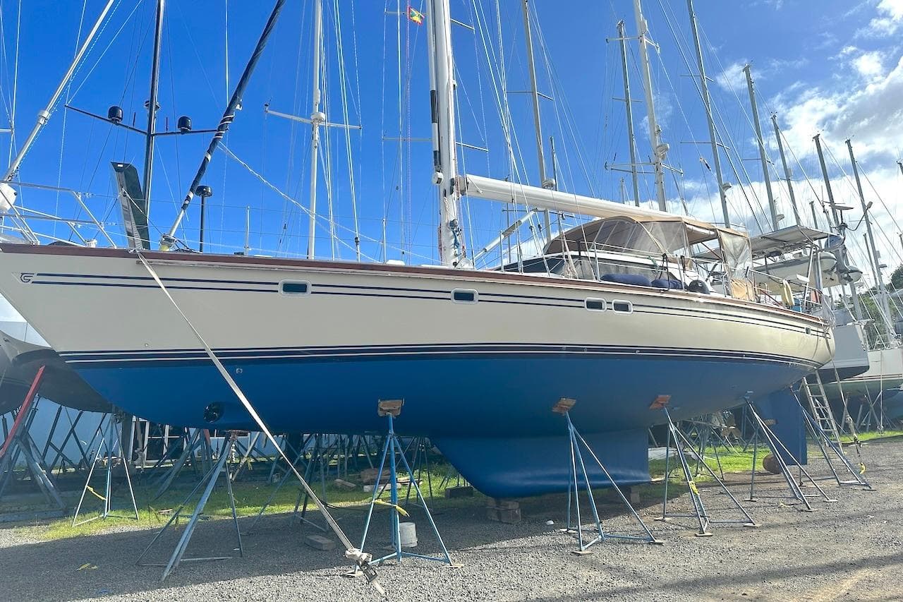 2003 Taswell 58 sailboat on stands, blue hull, white deck, clear sky background.