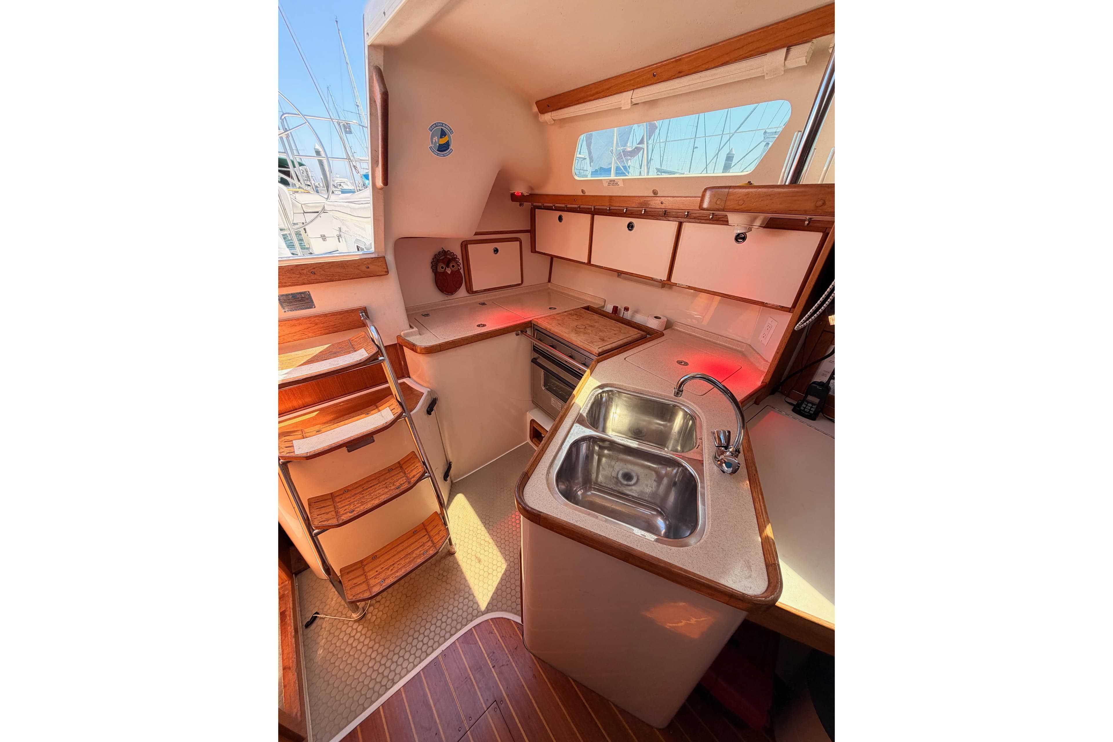 Interior of 1999 Catalina 320 sailboat kitchen with sink, stove, and wooden cabinetry.