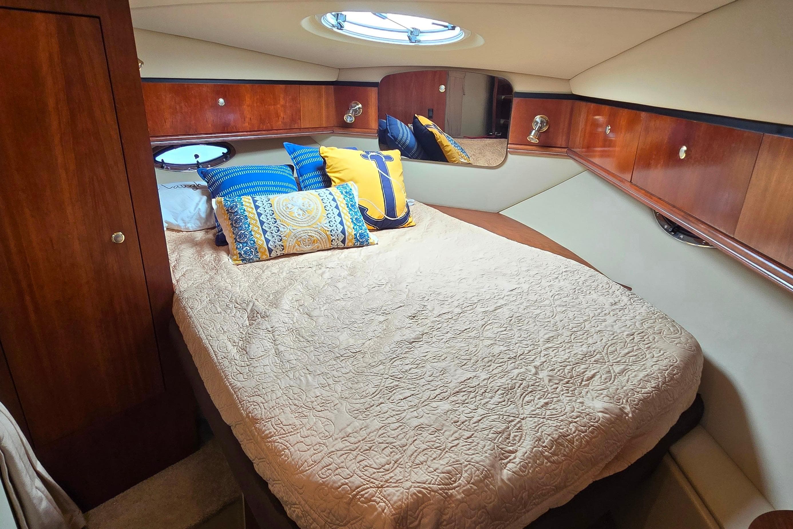 Luxurious cabin interior of 2005 Cruisers Yachts 340 Express with cozy bedding and elegant wood finish.