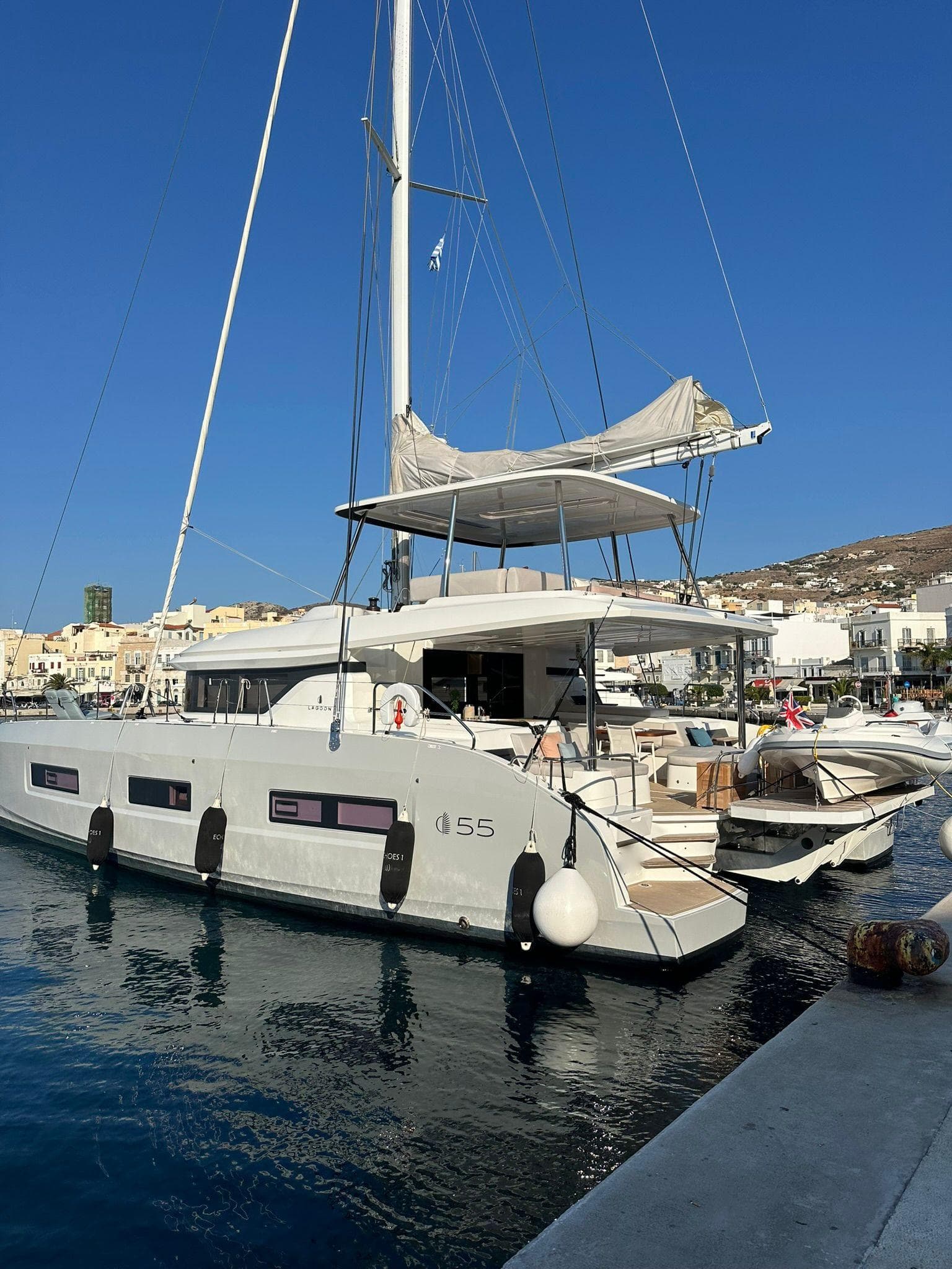 2023 Lagoon 55 yacht docked in a sunny marina, showcasing sleek design and modern features.