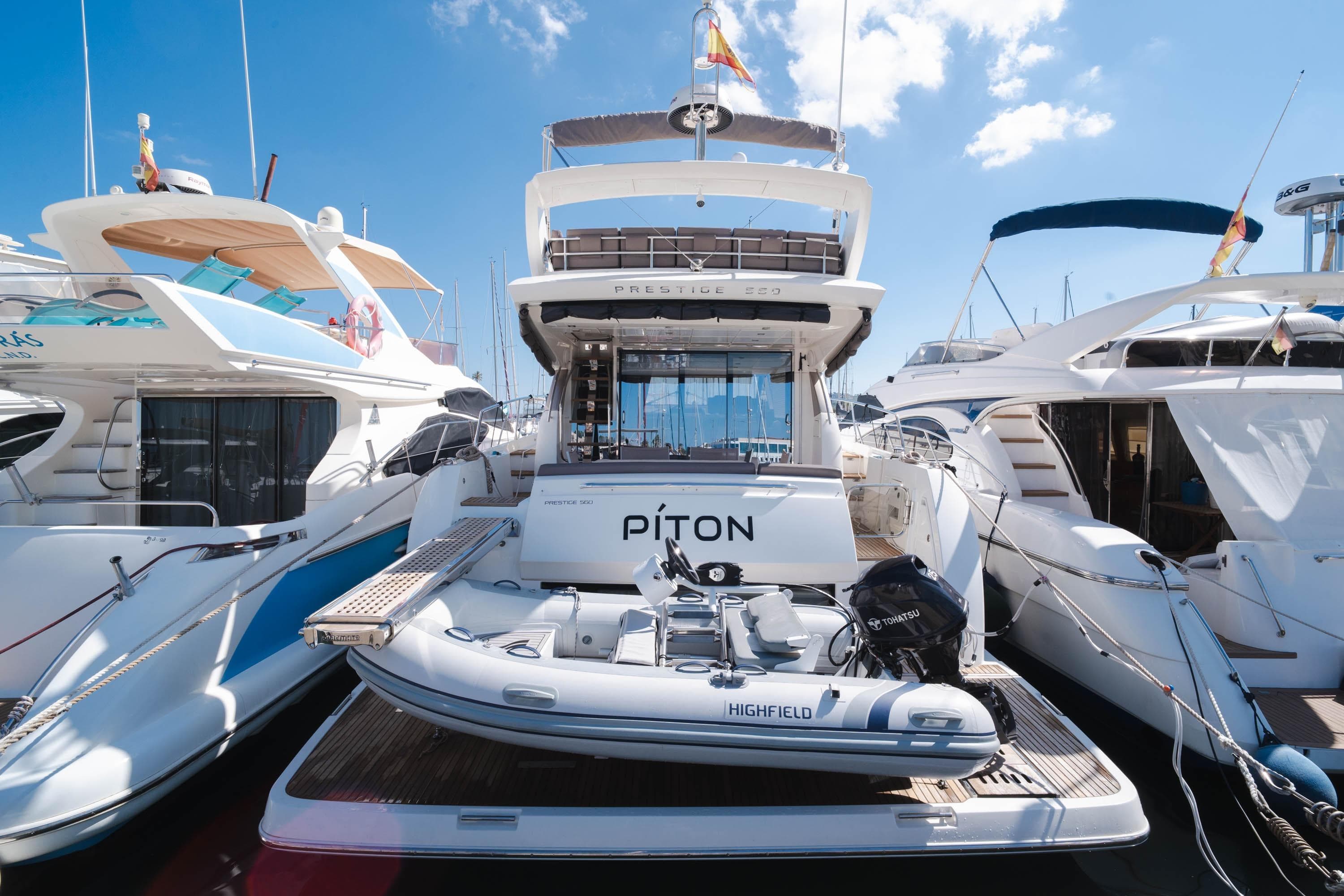 Luxury 2017 Prestige 560 yacht docked with inflatable boat, clear sky background.