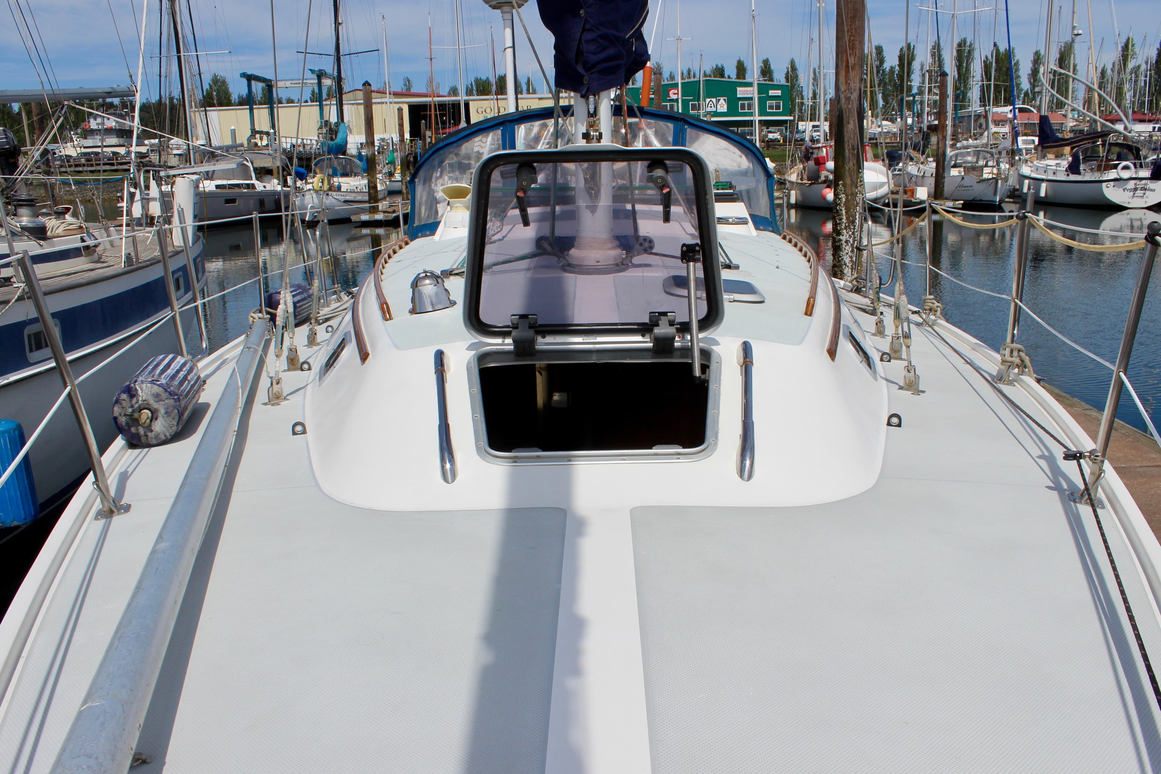 1989 Catalina 36 sailboat deck view in marina, open hatch, surrounded by other boats.