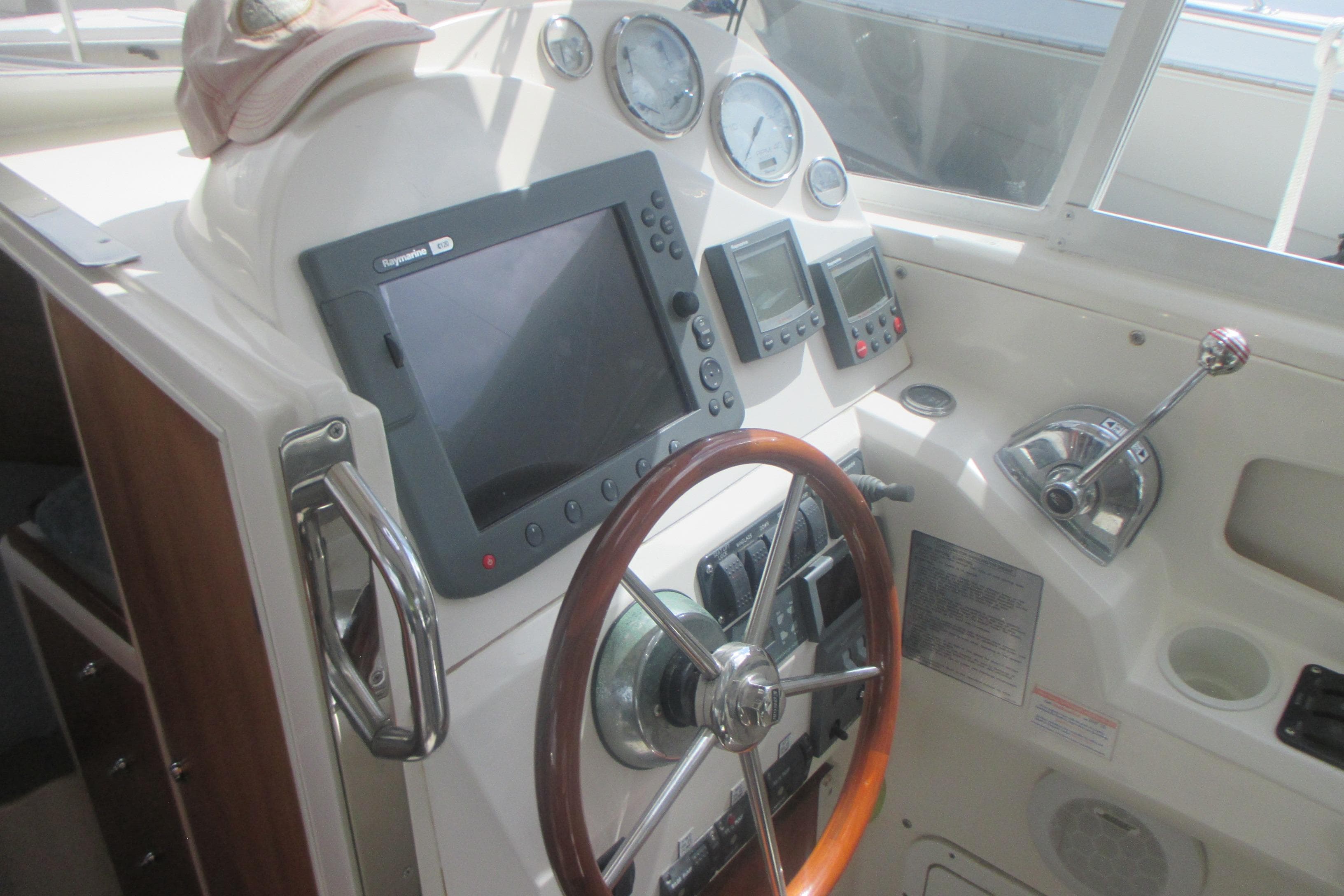 Helm of 2005 True North 33 boat with navigation equipment and wooden steering wheel.