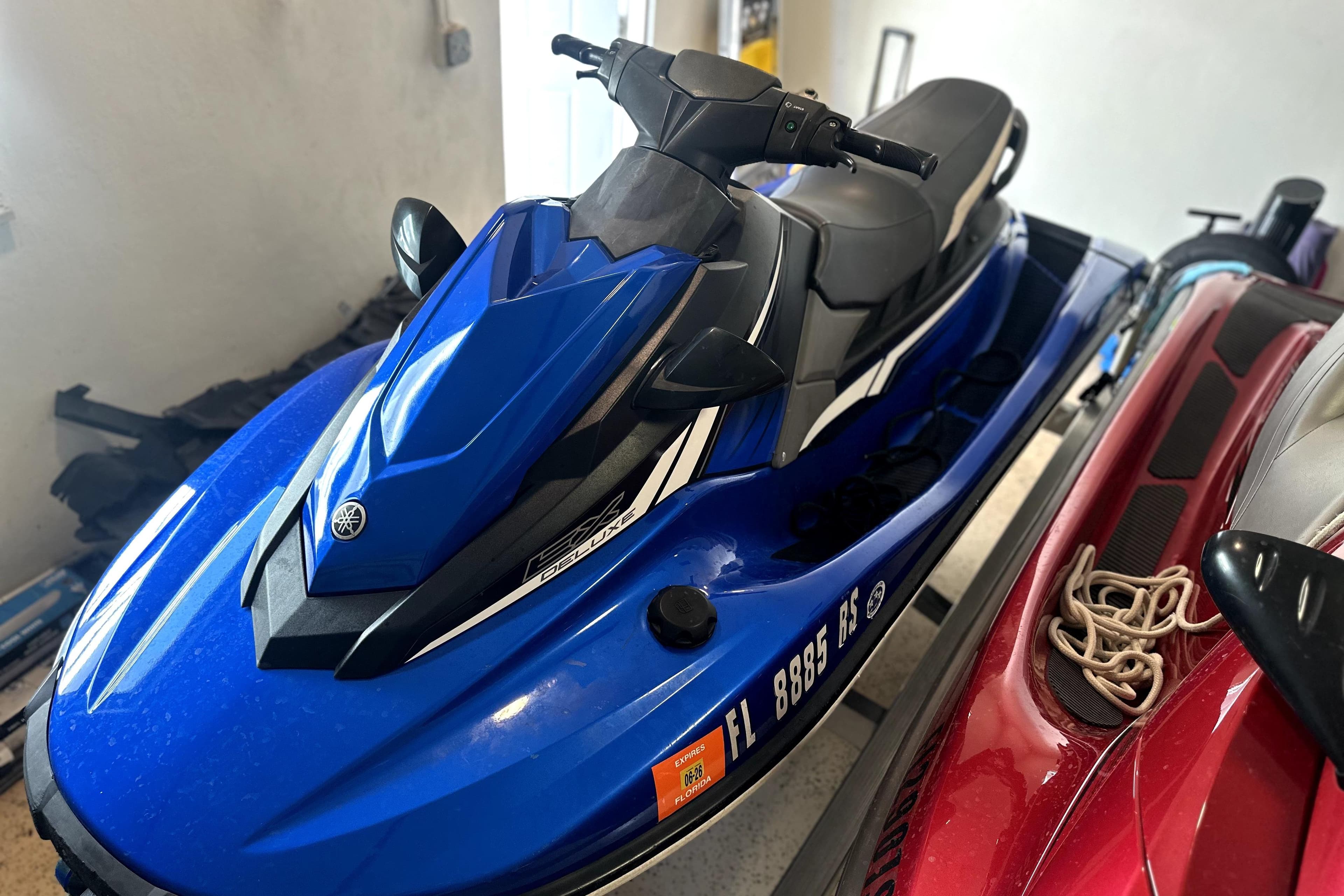 2018 Yamaha WaveRunner EX Deluxe in blue, parked indoors beside another watercraft.