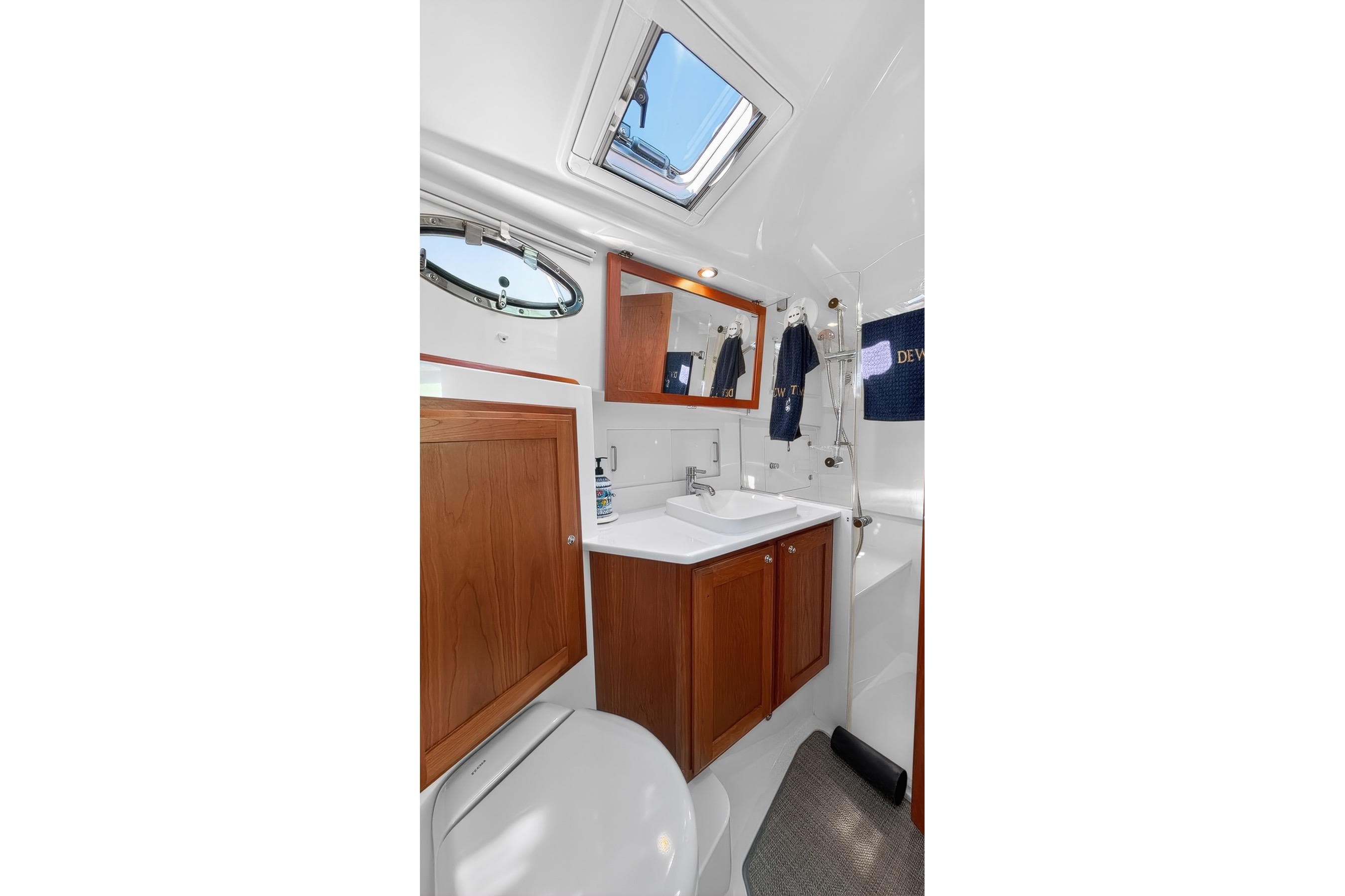 Luxurious Head interior of 2024 Back Cove 39O yacht, featuring wood cabinetry and modern fixtures.