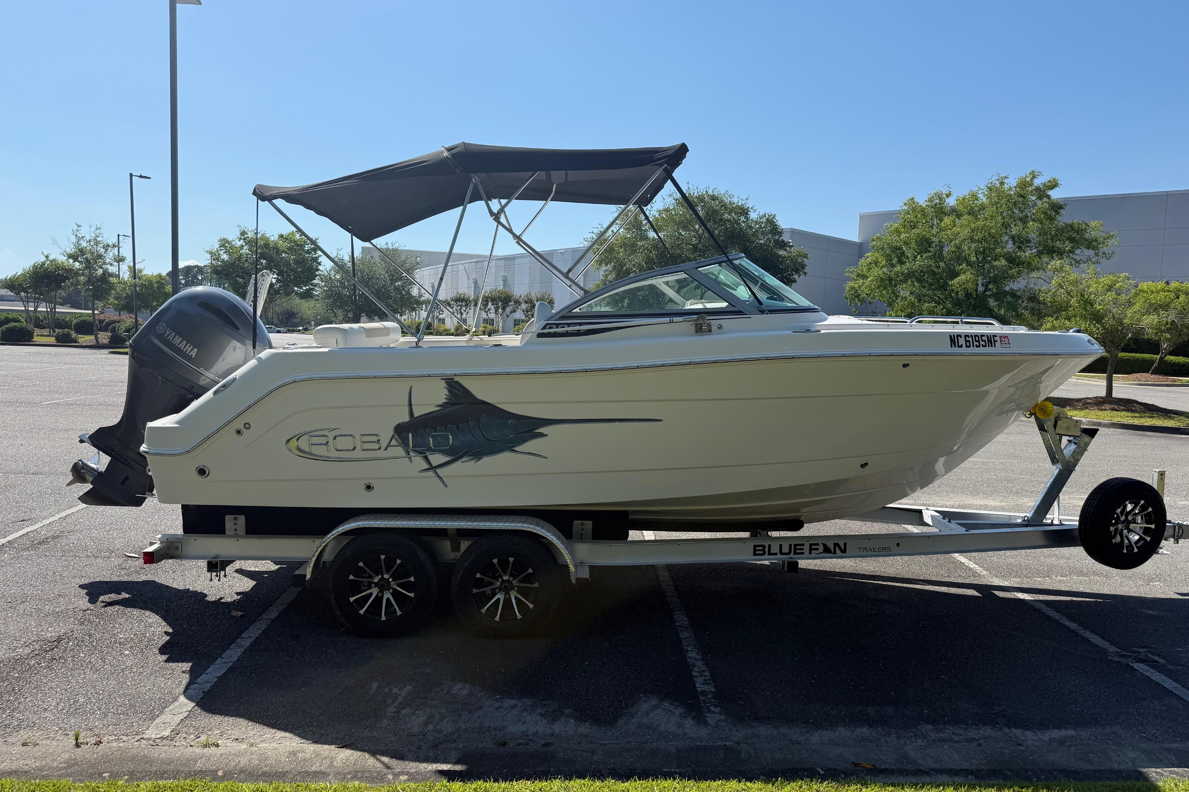 2015 Robalo R227 Dual Console boat on trailer in parking lot.