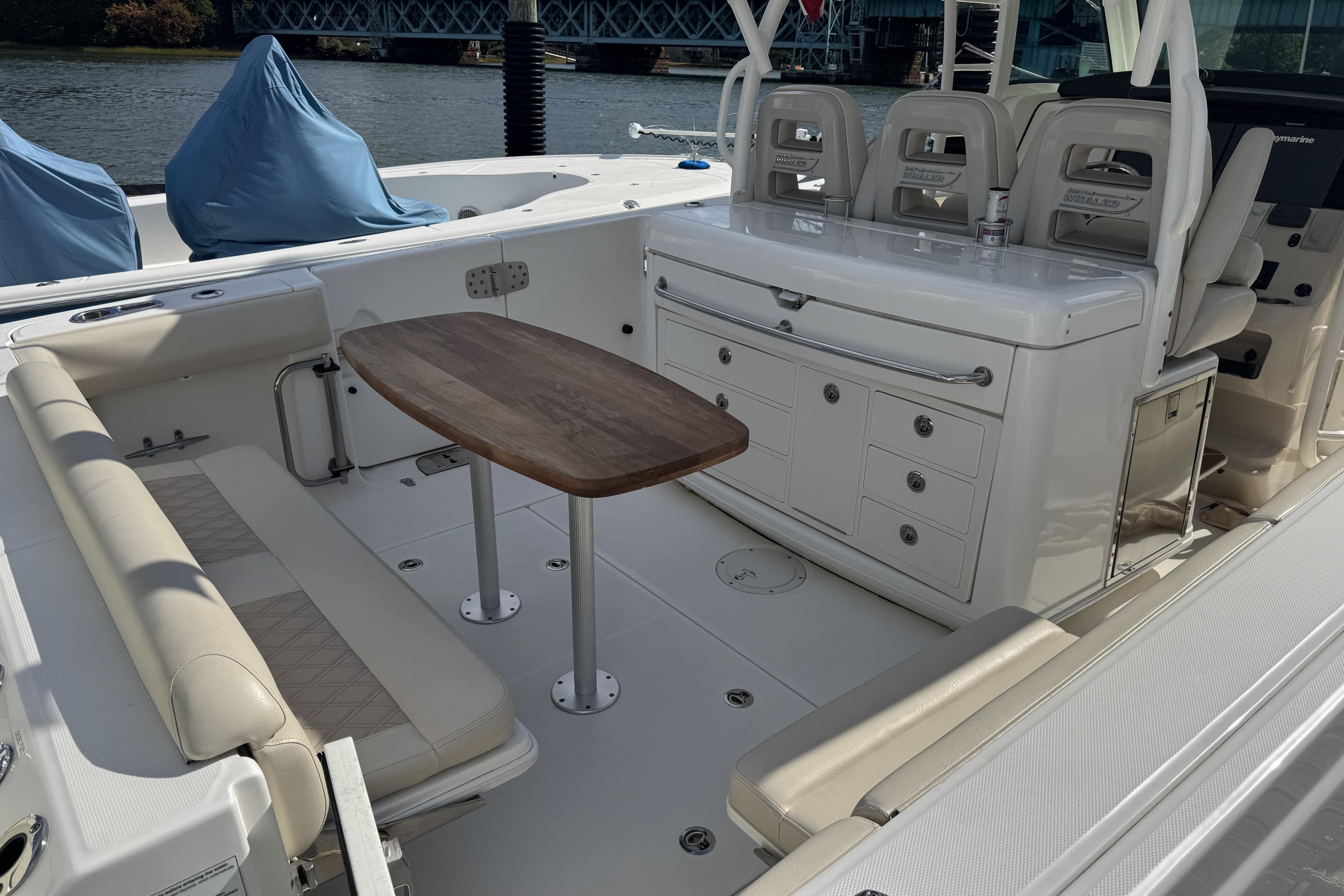 2017 Boston Whaler 370 Outrage interior with seating, table, and storage on a sunny day.