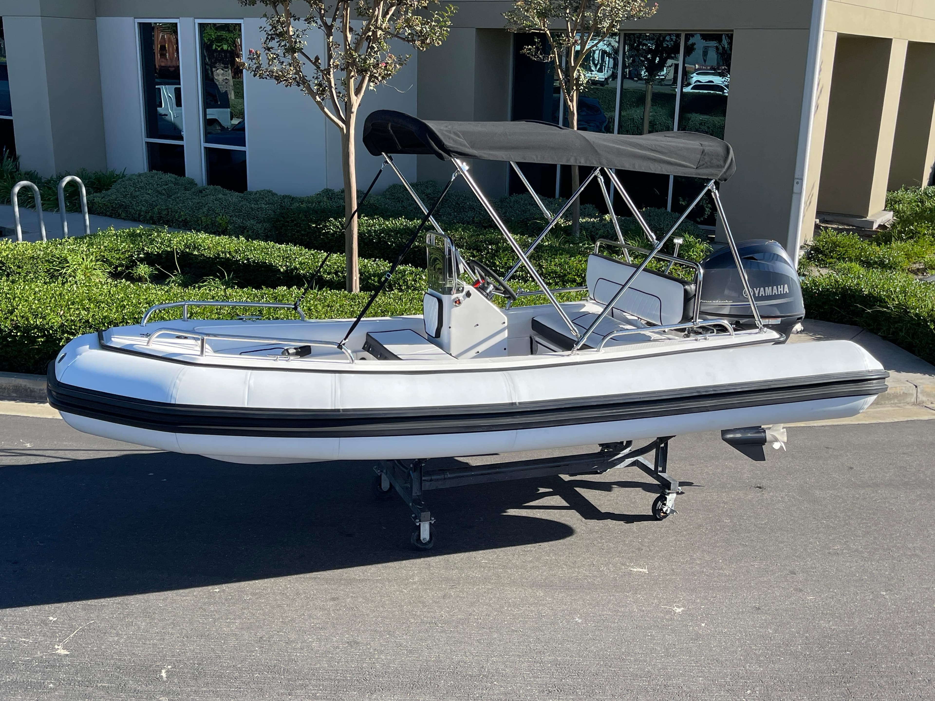 1998 Rendova 14 inflatable boat with canopy, parked outdoors.