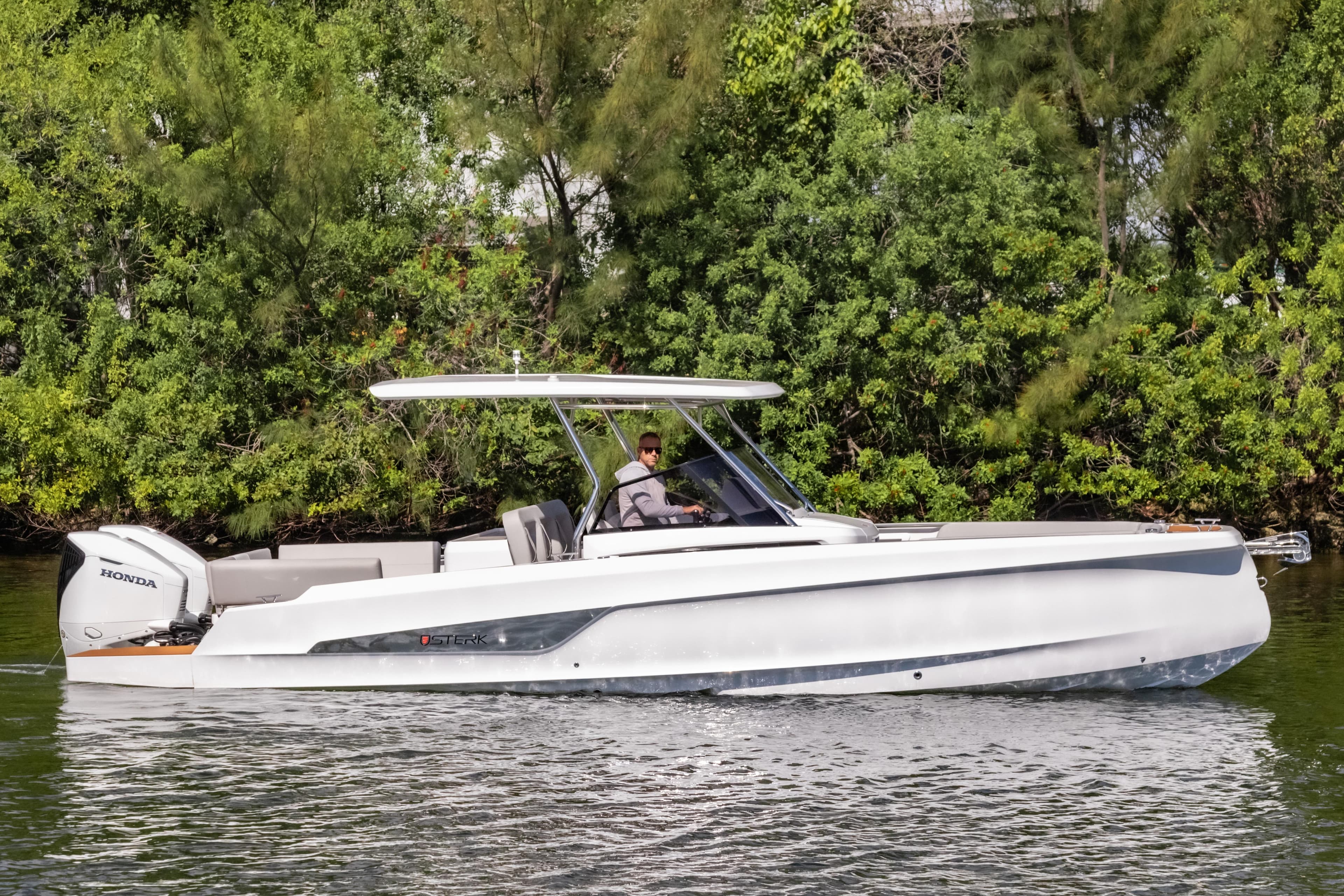 2025 STERK 31 boat cruising on a calm river with lush greenery background.