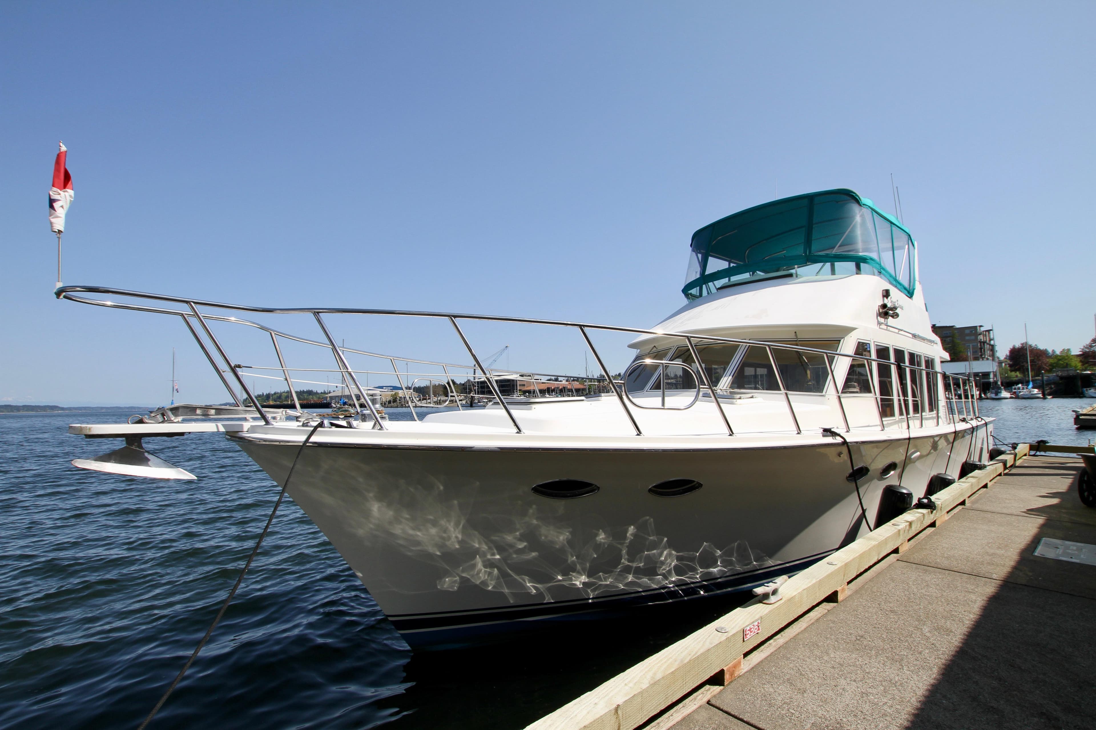 1999 McKinna 47 Sedan yacht docked by the waterfront on a sunny day.
