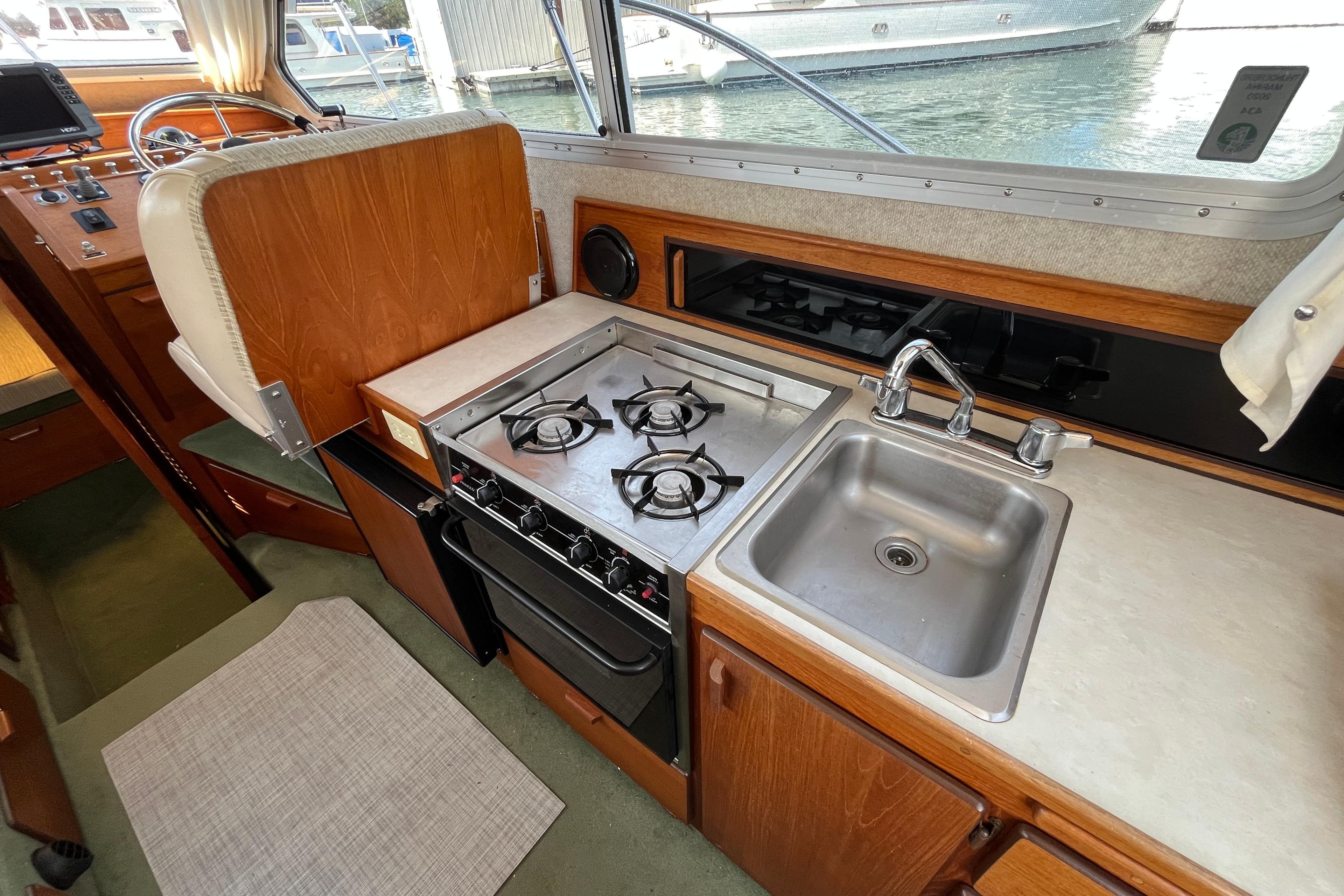 Compact boat kitchen with stove, sink, and wooden cabinetry, featuring a 2006 Commander Sedan.