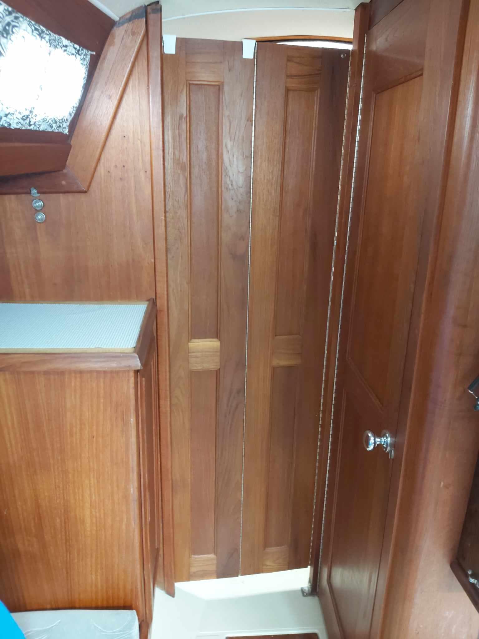Interior of 1978 Ericson 30-2 sailboat with wooden cabinetry and folding door.