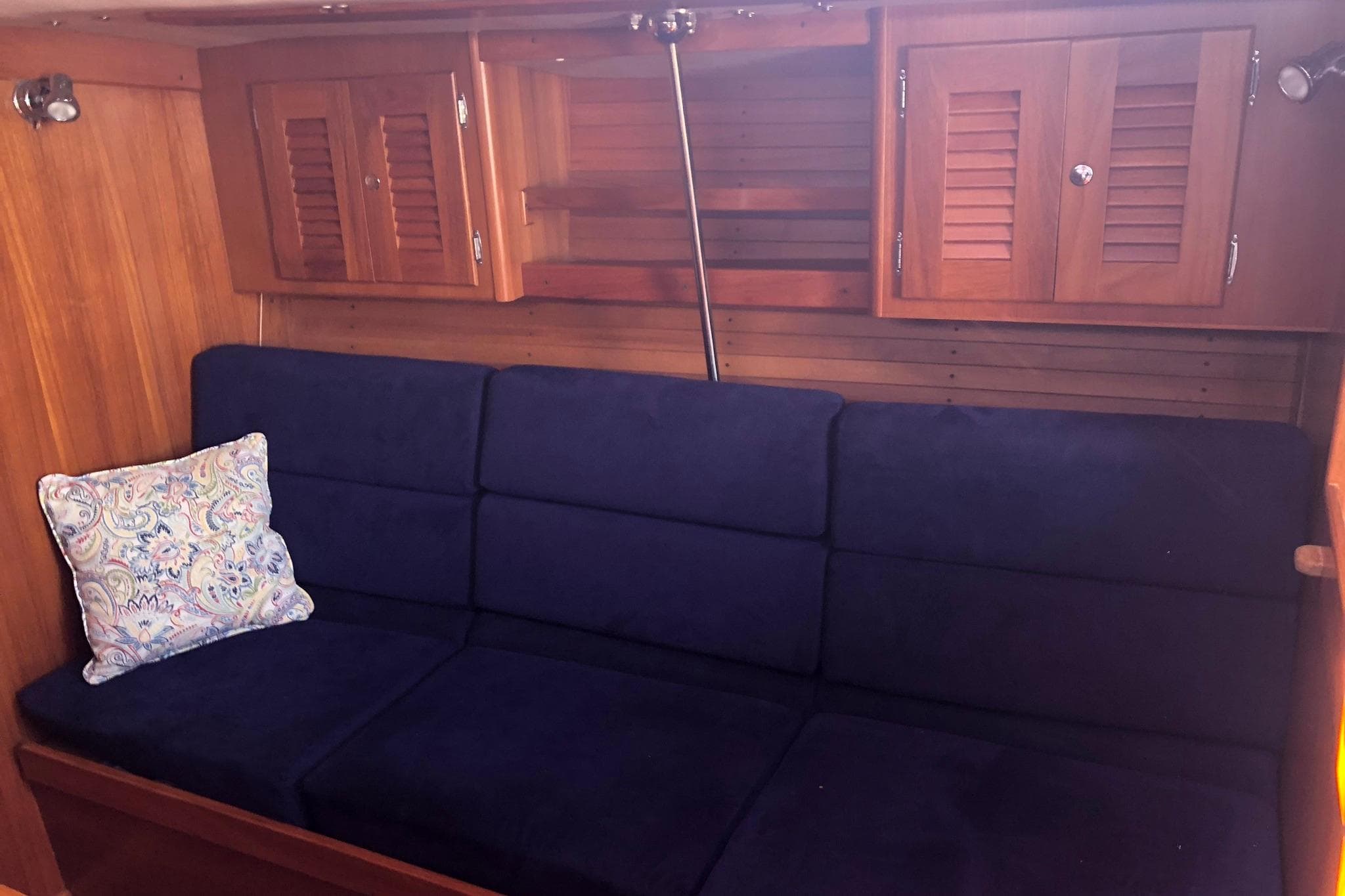 Interior of 2004 J Boats J/133 with blue sofa and wooden cabinets.