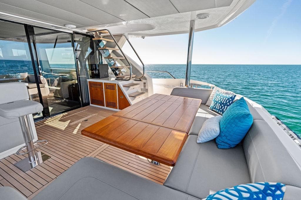 Luxurious 2019 Sunseeker 76 Yacht deck with ocean view, featuring elegant seating and wooden table.