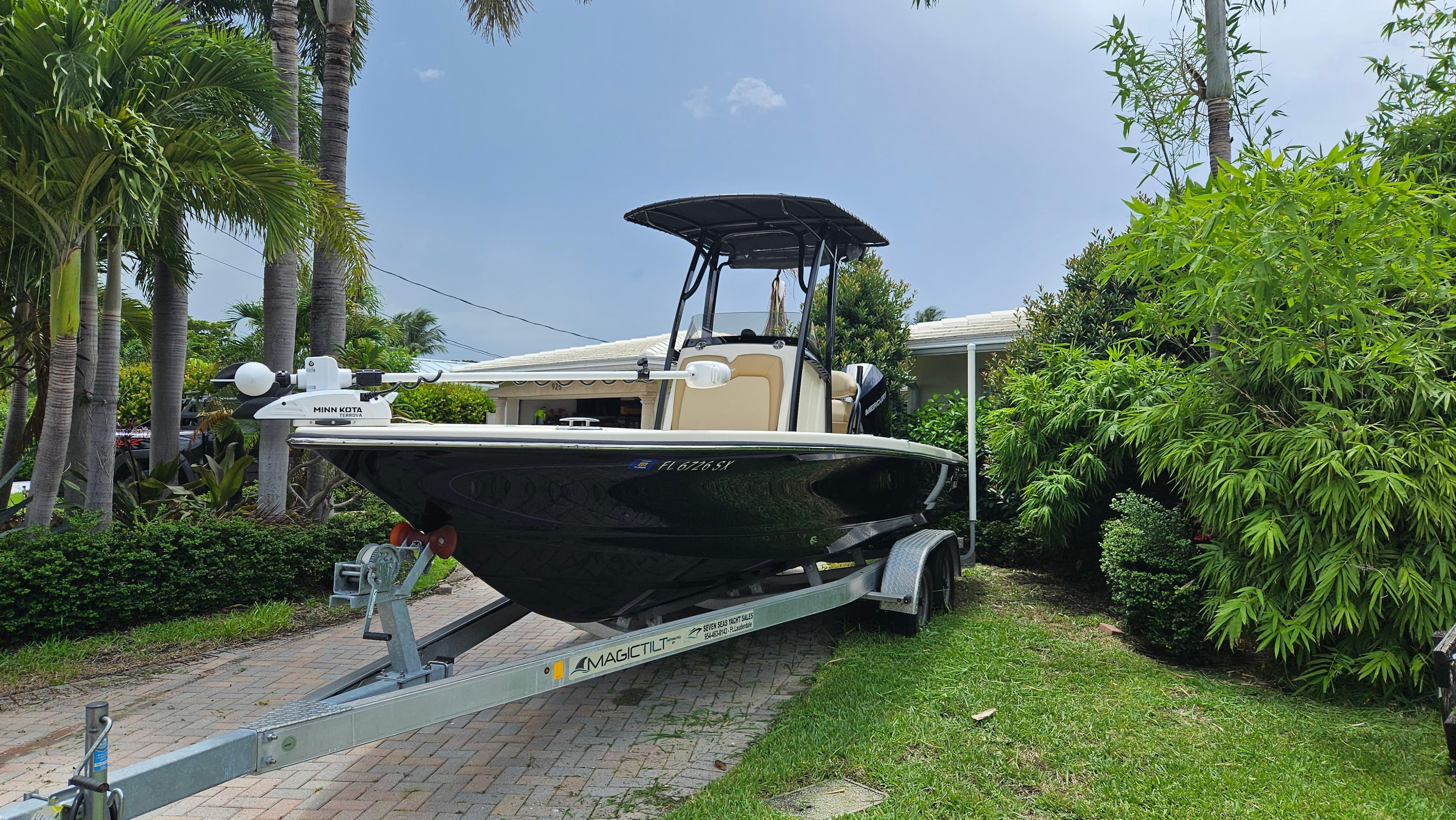2021 Scout 231 XS boat on trailer, surrounded by lush greenery and palm trees.