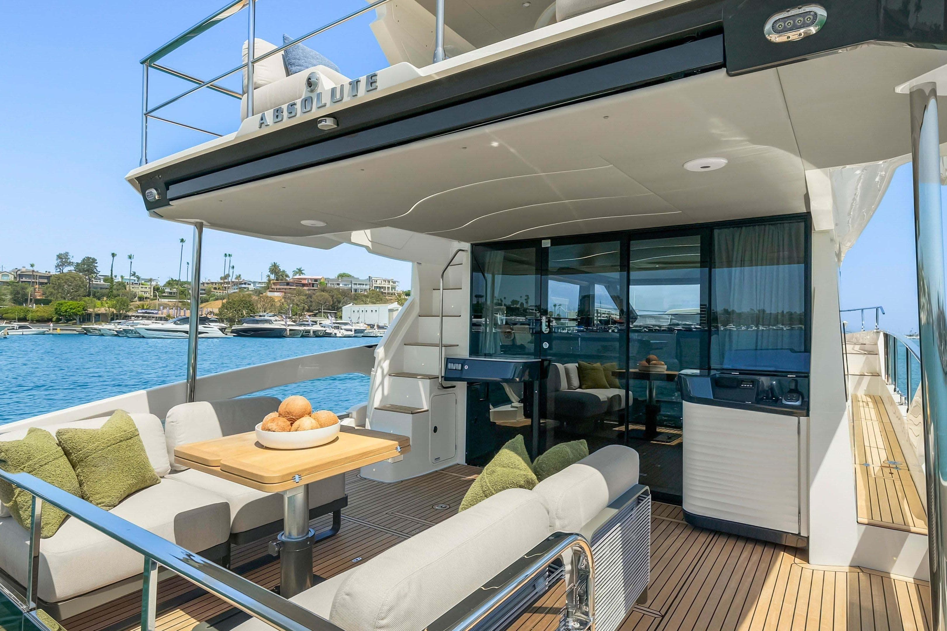 Luxurious 2026 Absolute 52 Fly yacht with elegant outdoor seating and scenic waterfront view.