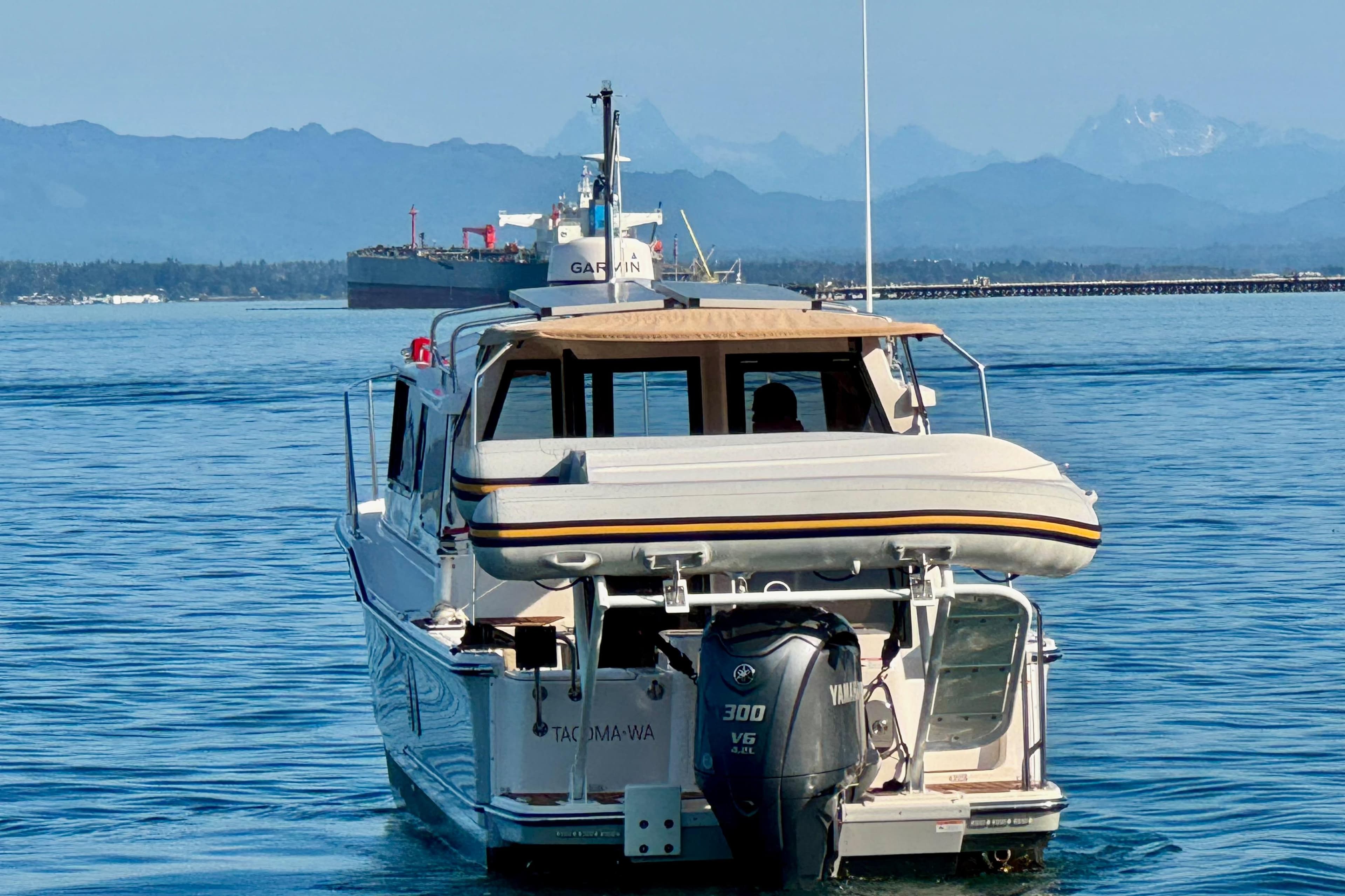 2024 Ranger Tugs R-27 boat cruising on calm waters with mountains in the background.
