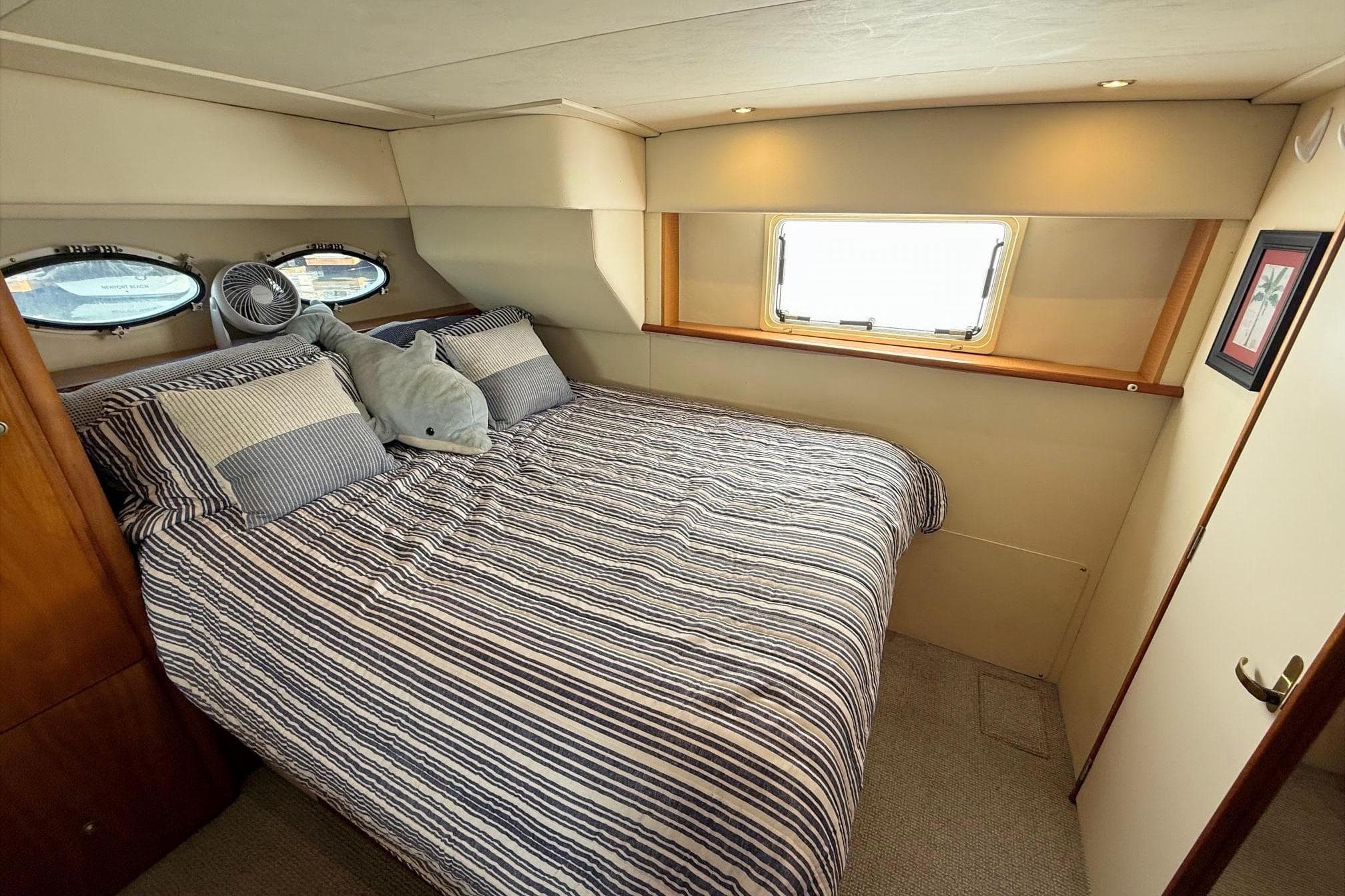 Cozy bedroom in 1999 Silverton 392 Motor Yacht with striped bedding and porthole windows.