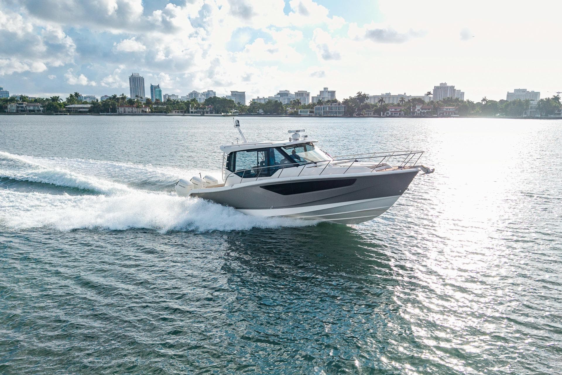 2024 Boston Whaler 405 Conquest cruising on a sunny day near city skyline.