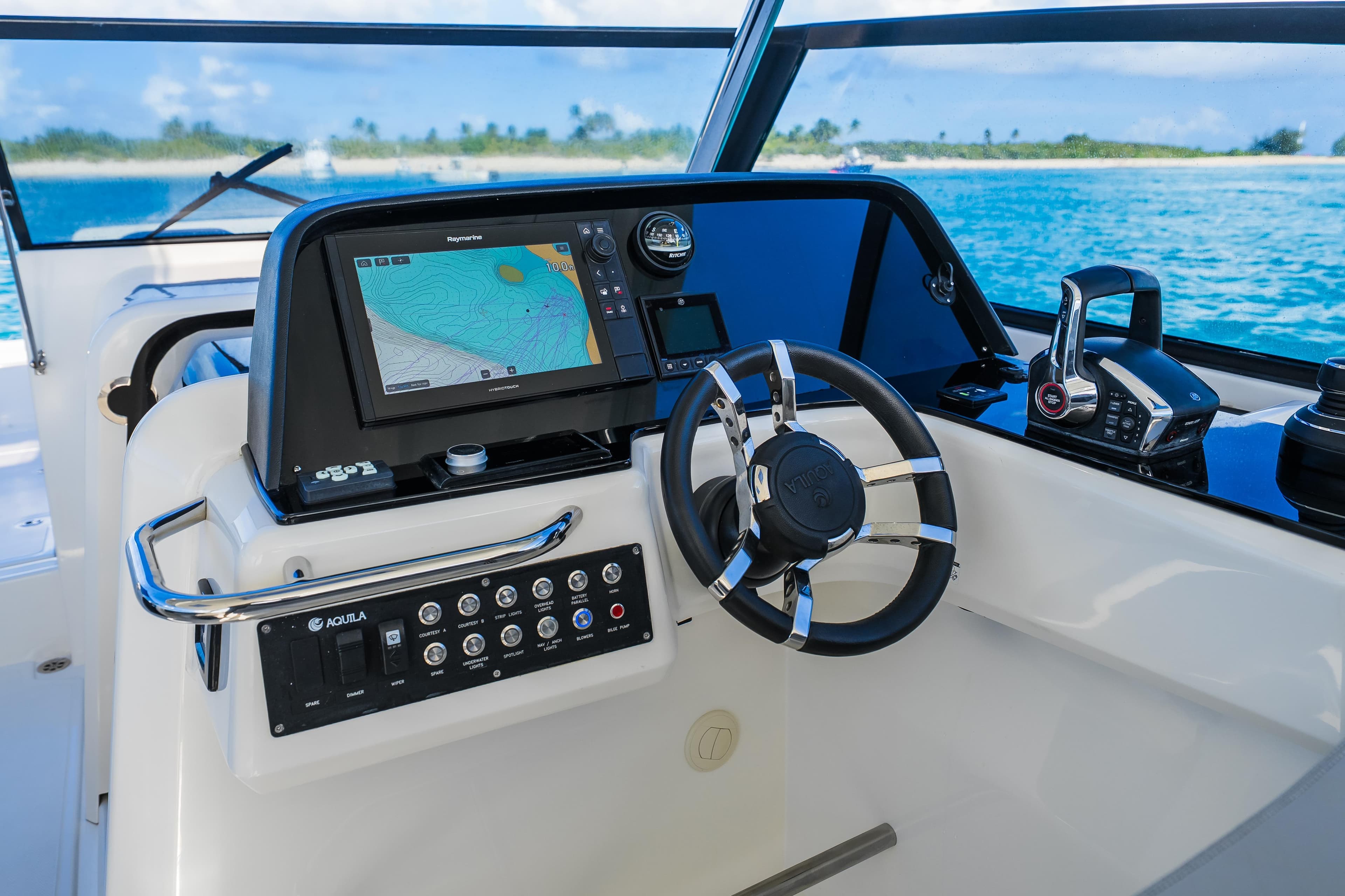 2023 Aquila 36 Sport helm with navigation display and controls, overlooking ocean view.