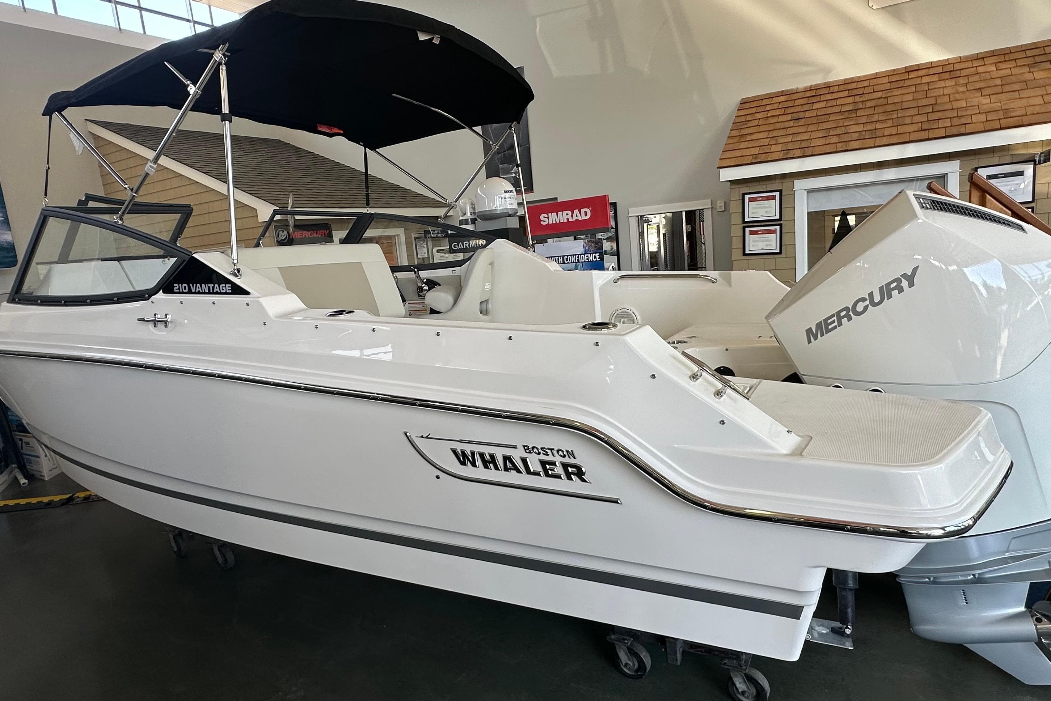 2026 Boston Whaler 210 Vantage boat with Mercury engine in showroom.