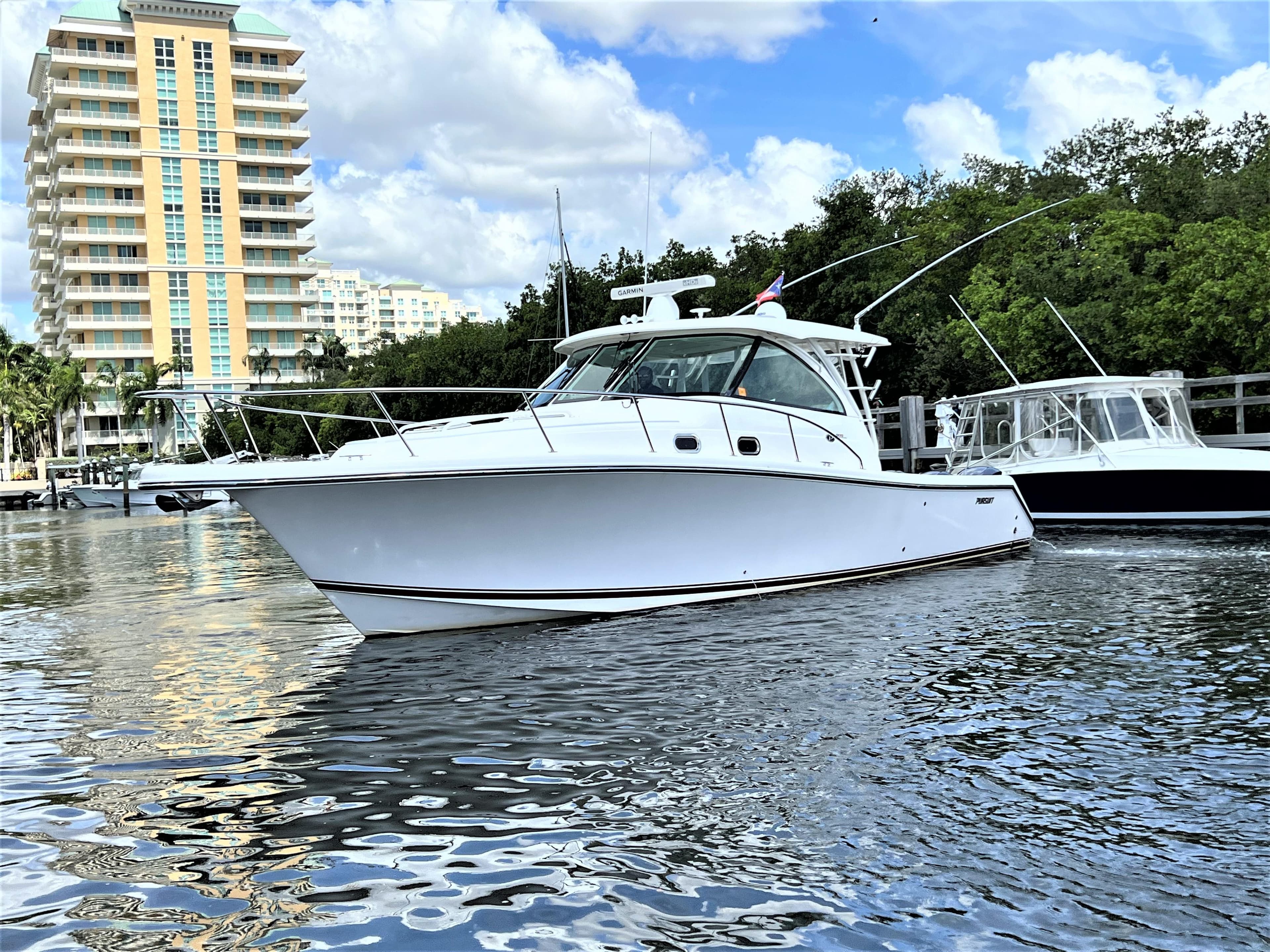 2016 Pursuit OS 385 Offshore boat docked near high-rise buildings.