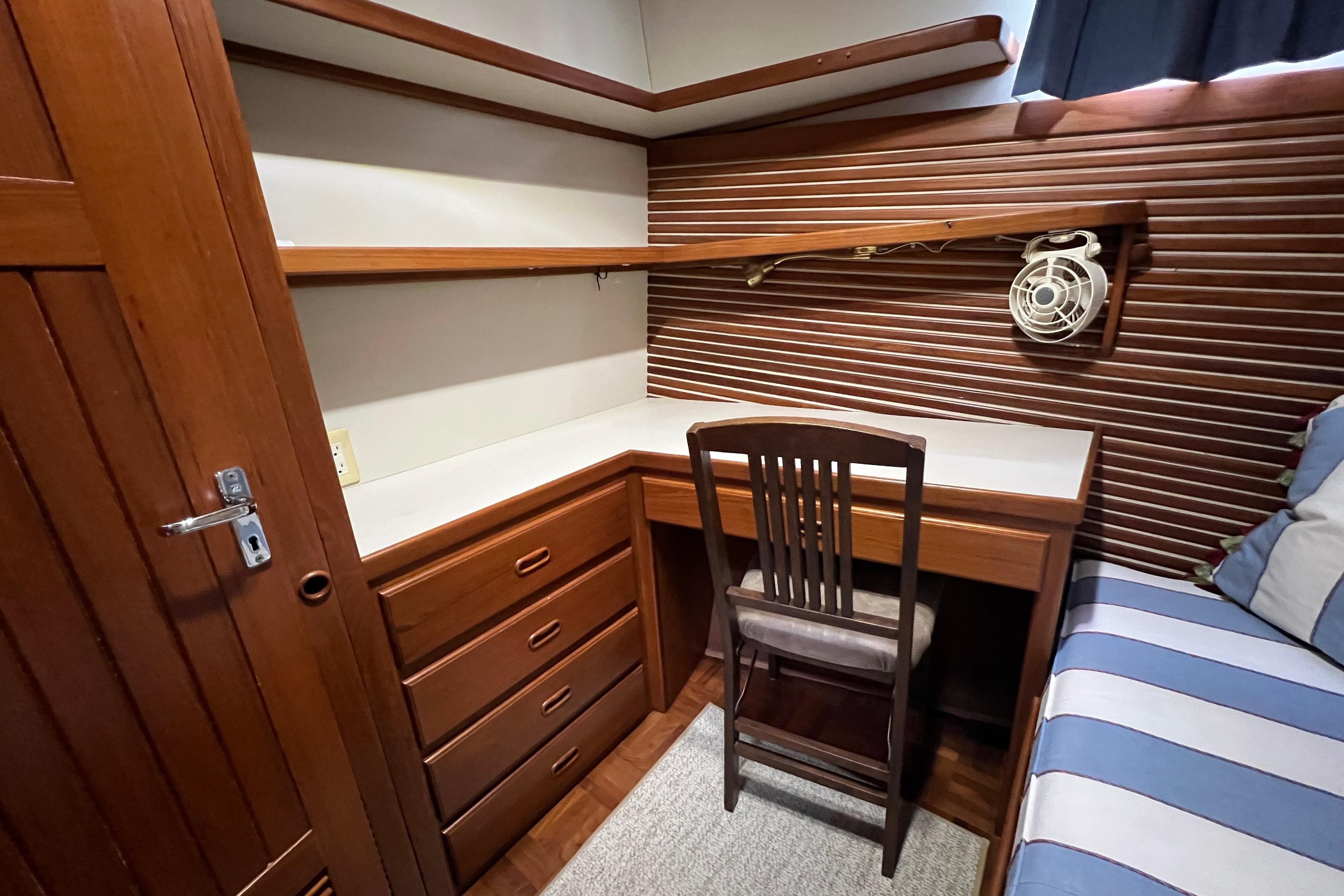 Cozy wooden cabin interior with desk, chair, and striped seating on a 1996 Kadey-Krogen 48 Whaleback.