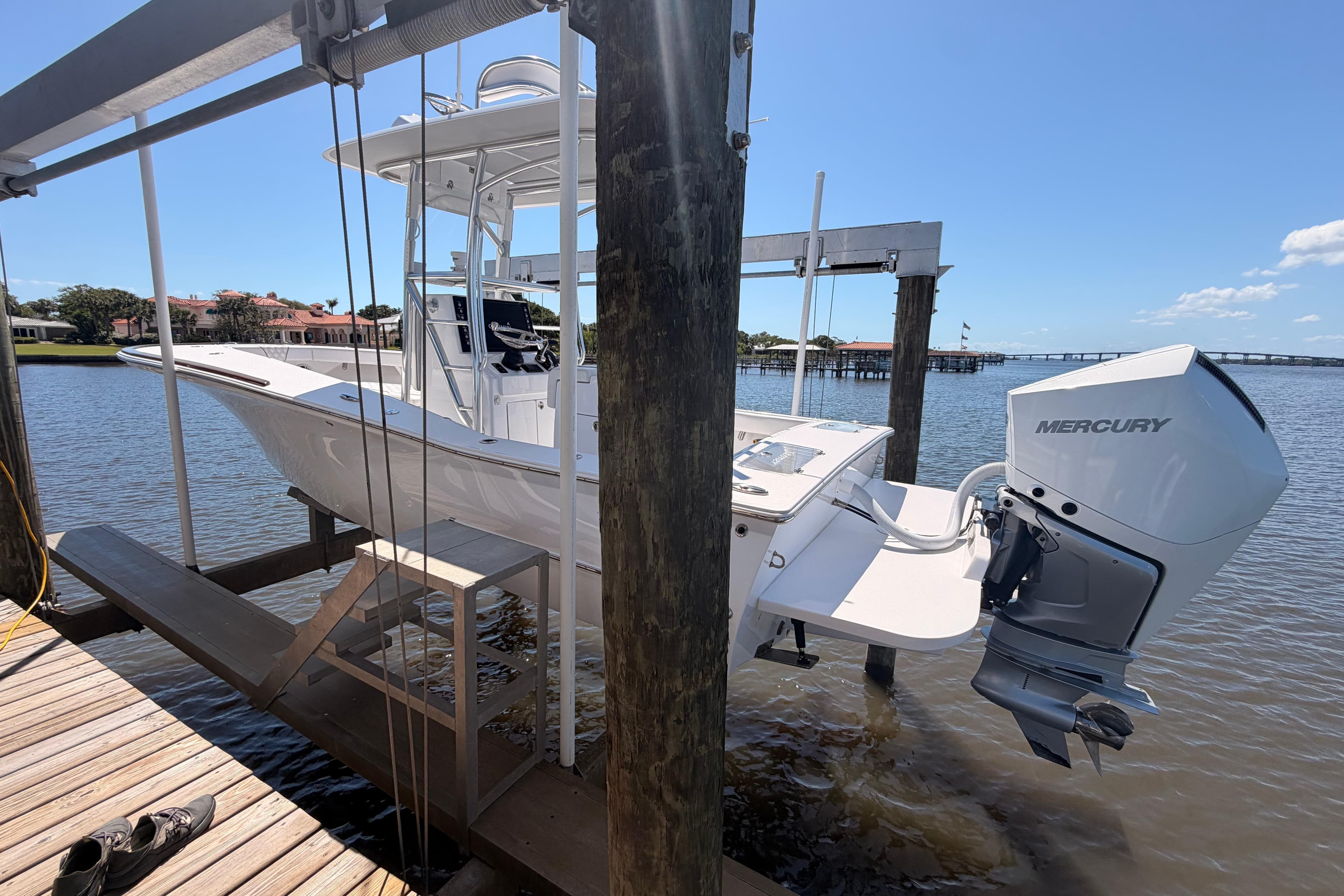 2024 Stoner 23 CC boat with Mercury engine on a lift by the water.