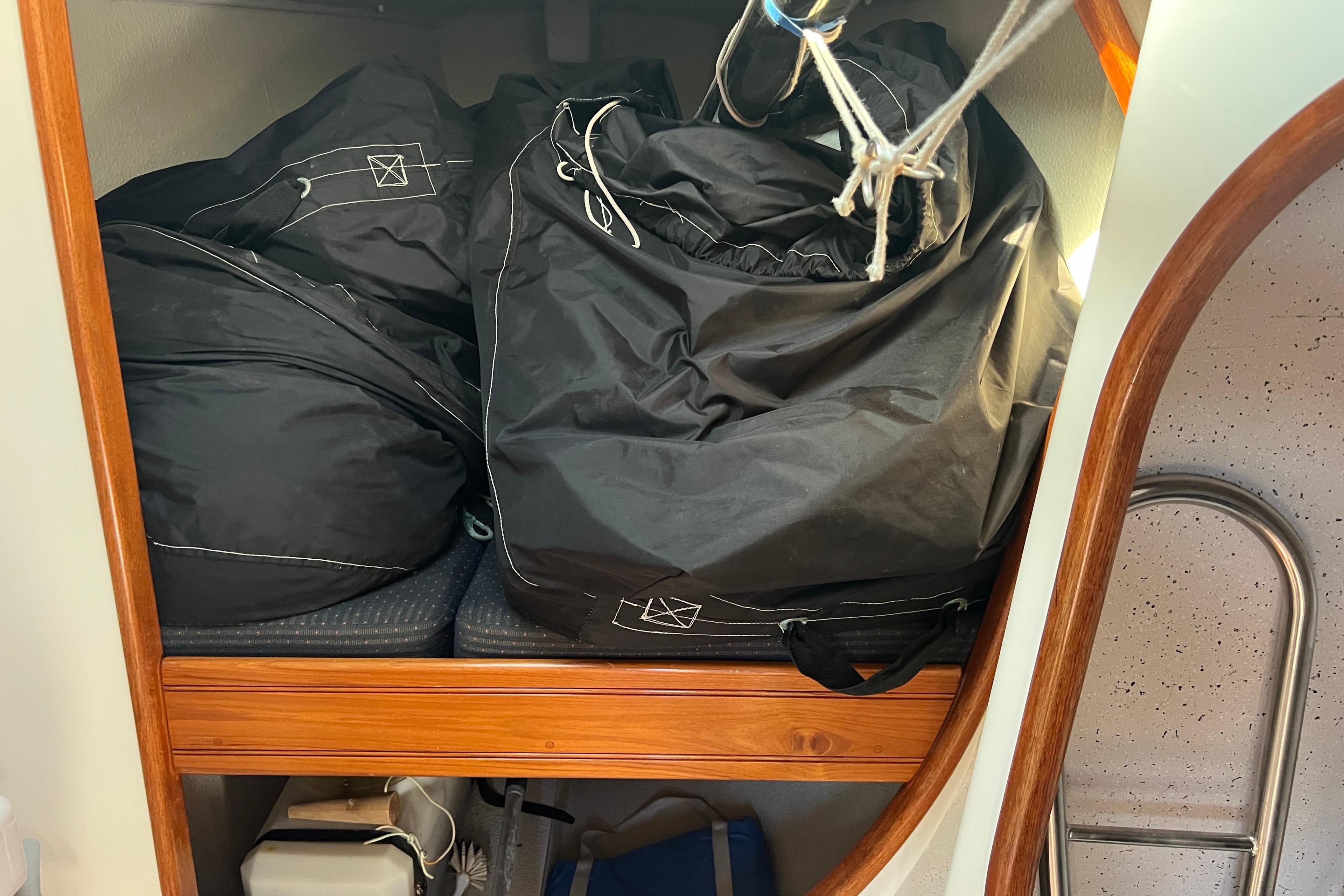 Black sail bags stored in a wooden compartment on a Sydney 32 sailboat.