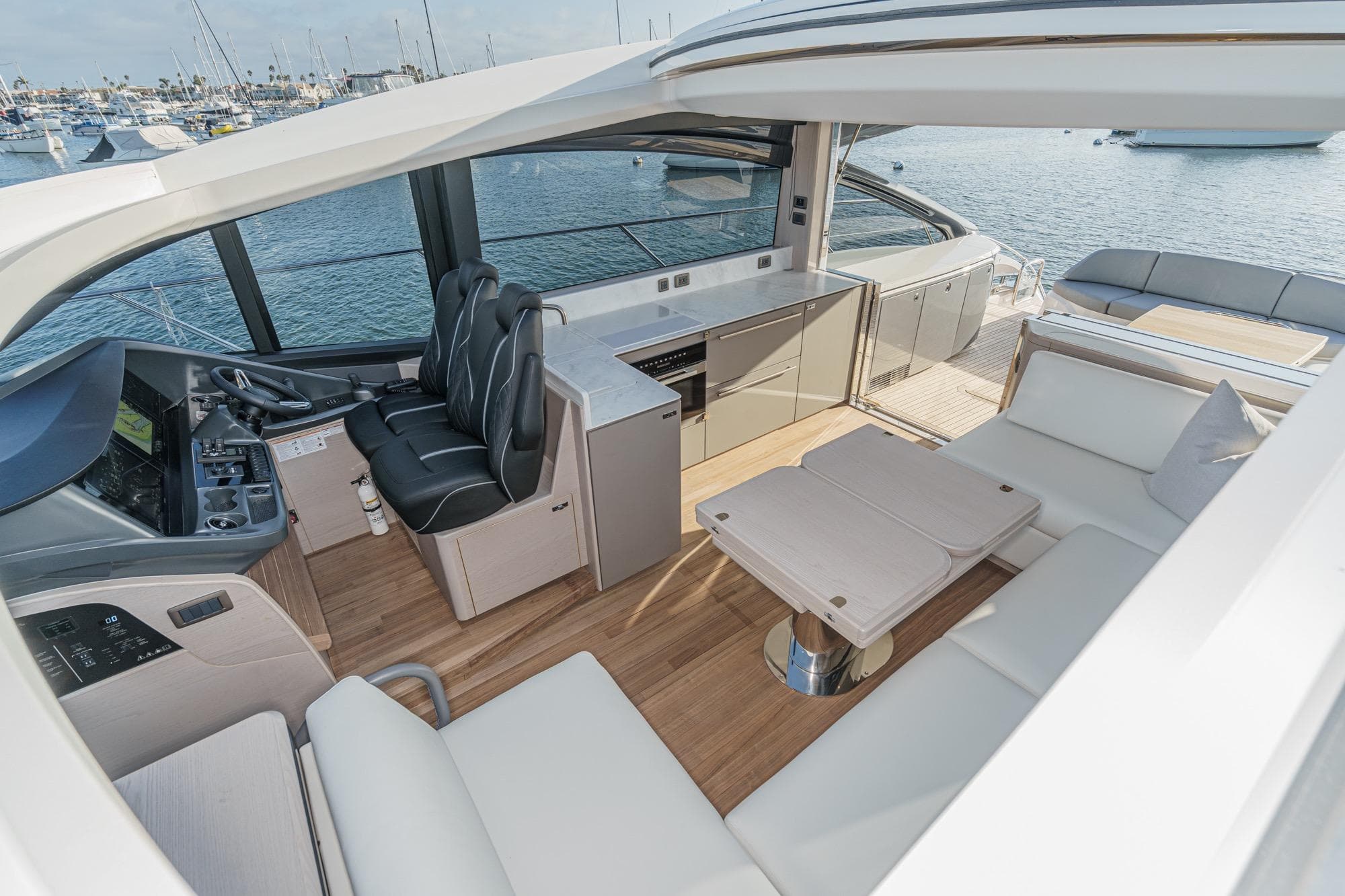 Luxurious 2026 Princess V55 yacht interior with modern seating and helm, overlooking serene waters.