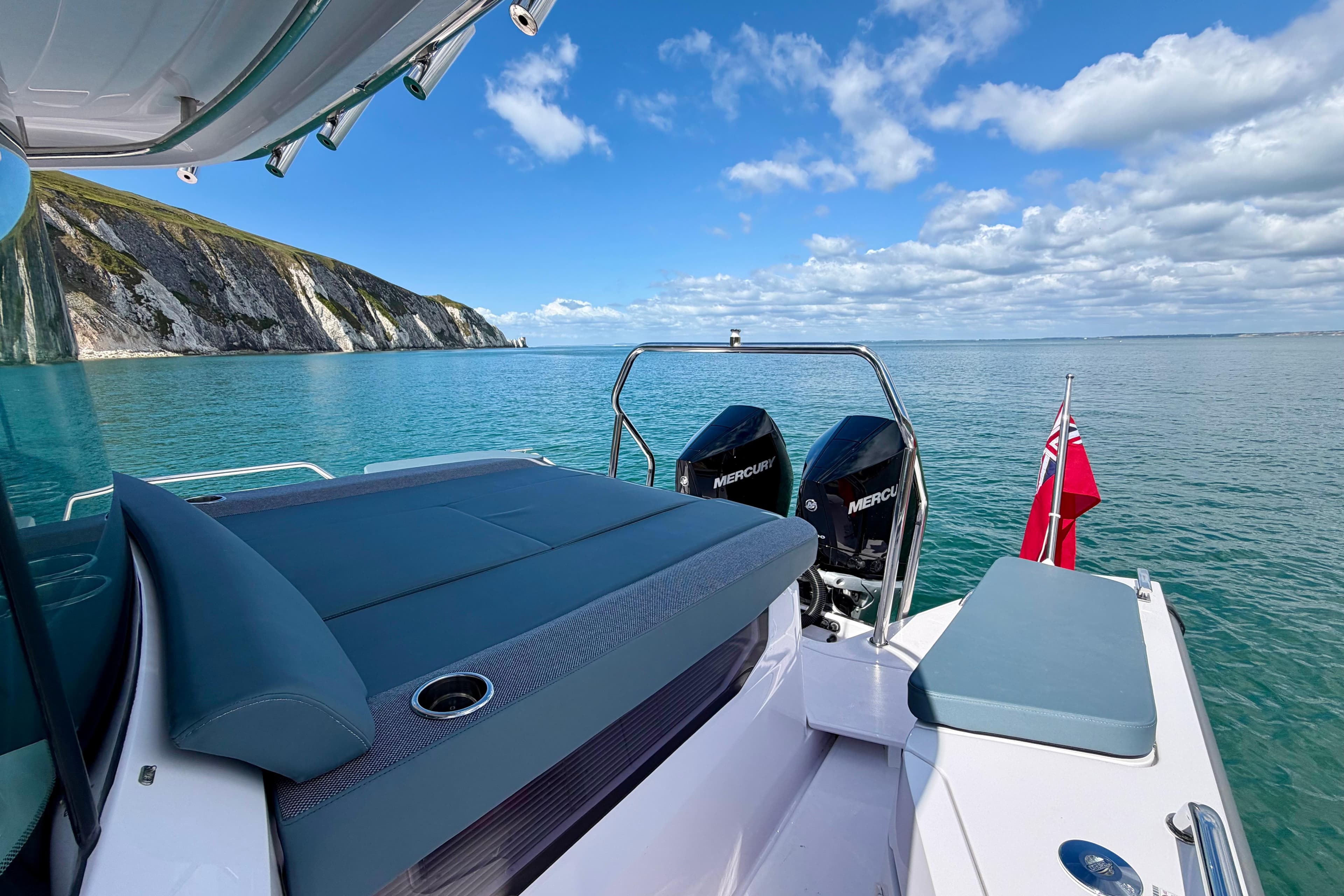 2024 Axopar 37 XC Cross Cabin on serene ocean with scenic cliffs.