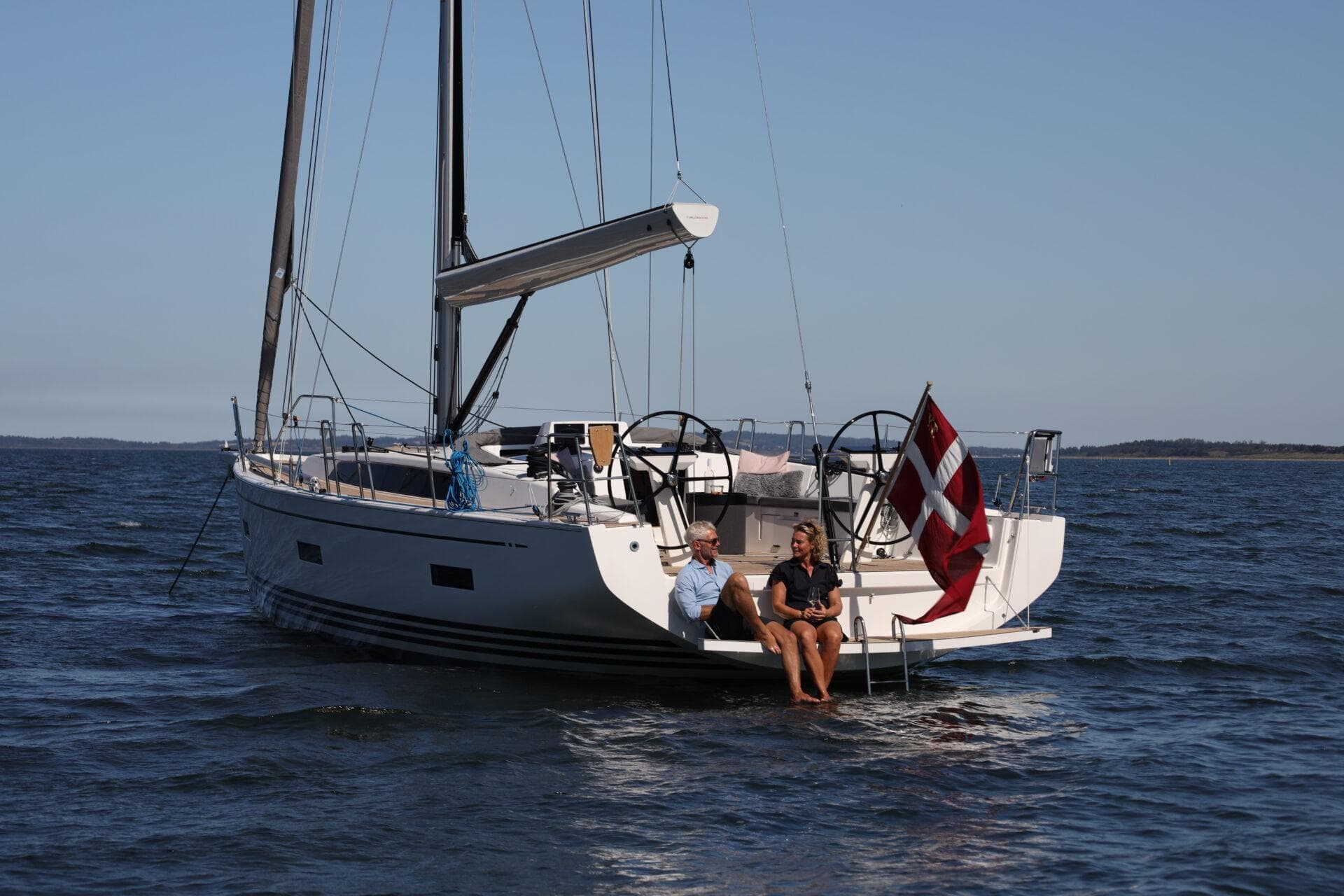 2026 X-Yachts X4 3 sailboat with two people, Danish flag, calm sea.