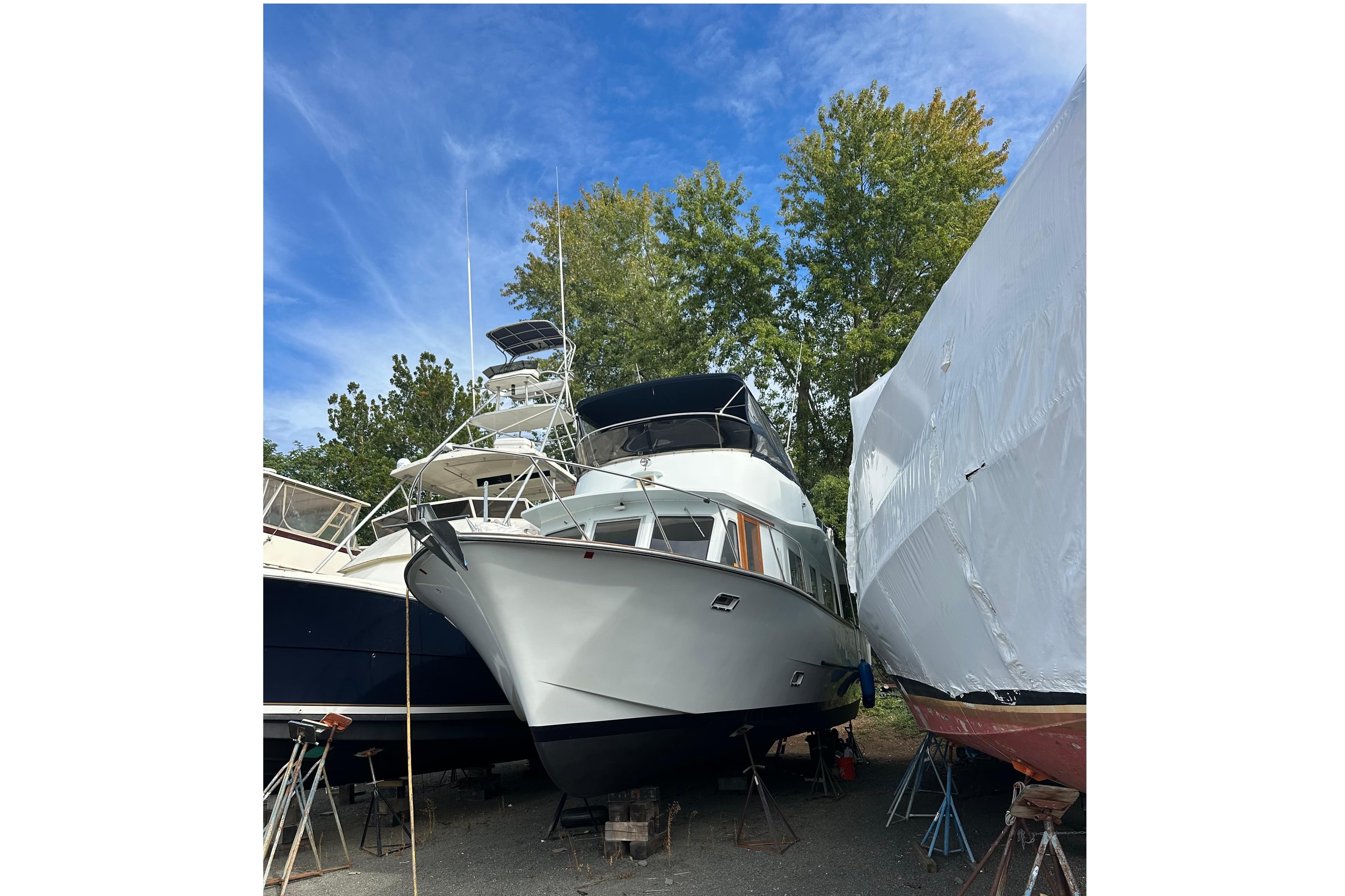1985 Pearson 43 Trawler on land, surrounded by trees and other boats.