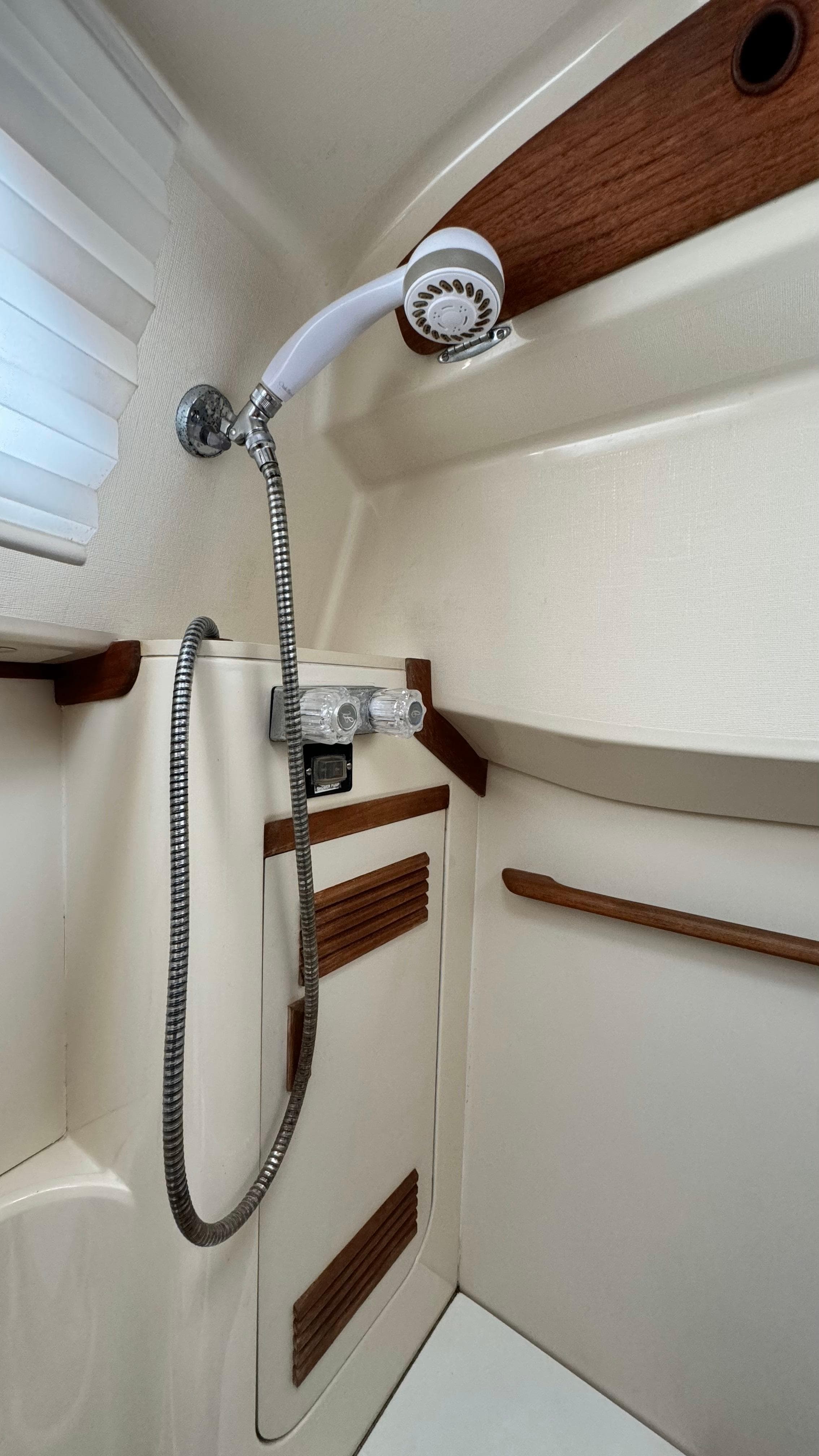 1990 Sabre 38 yacht shower with wood accents and handheld showerhead.