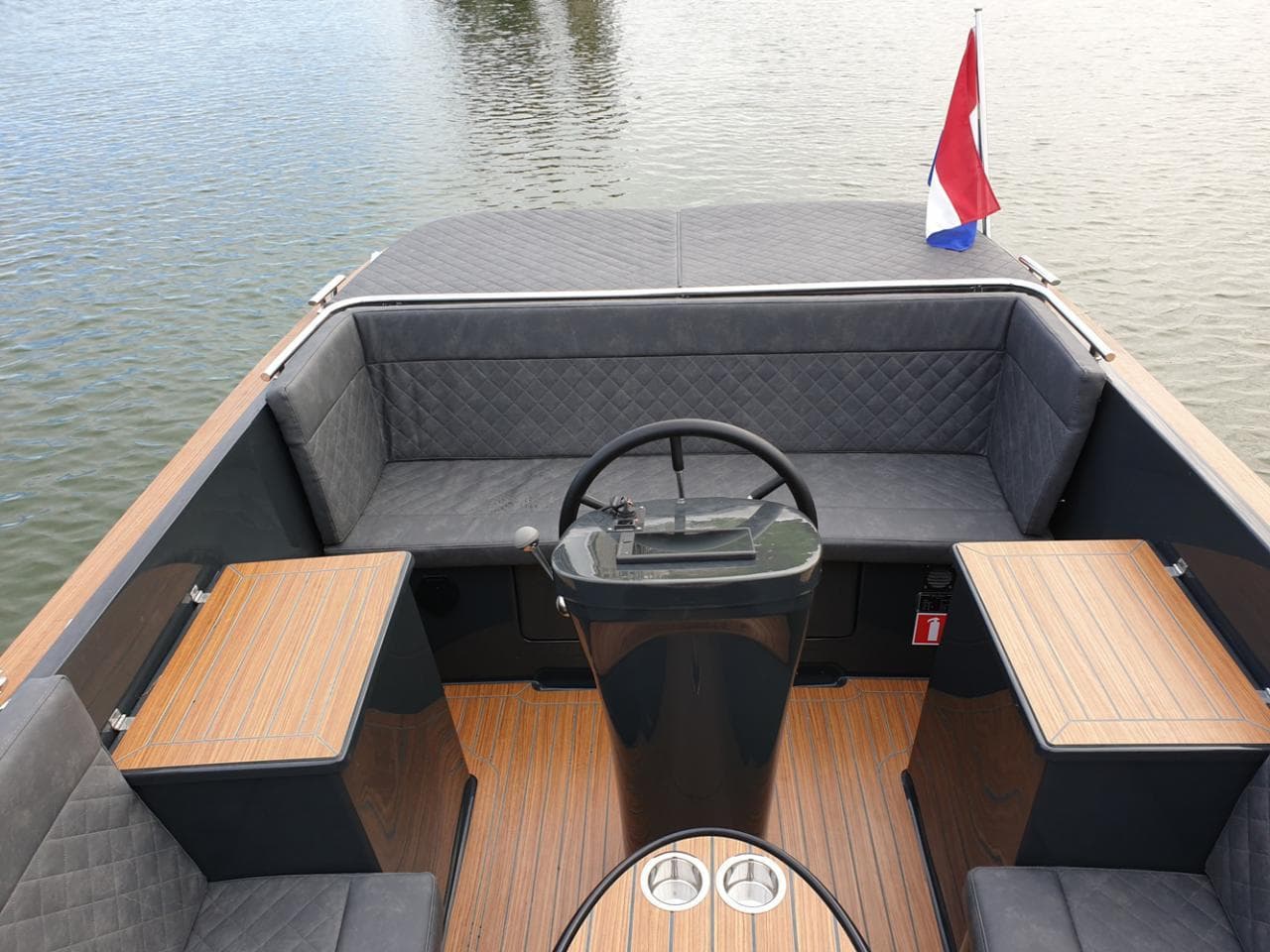 2023 Maxima 620 Retro boat interior with steering wheel and seating, on calm water.