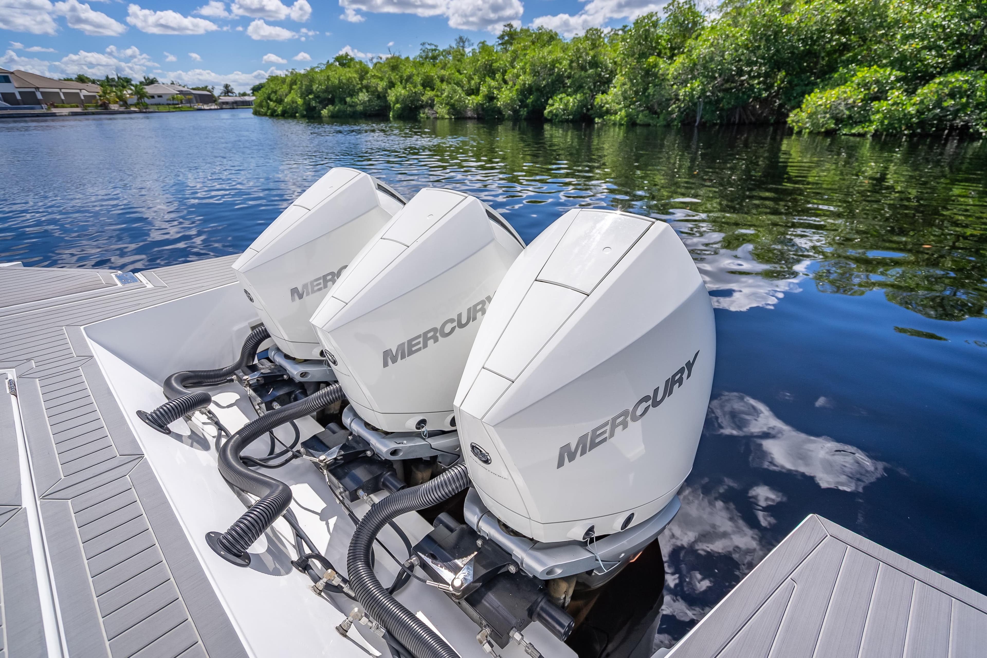 2022 Cruisers Yachts 38 GLS OB with triple Mercury outboard engines on a serene waterway.