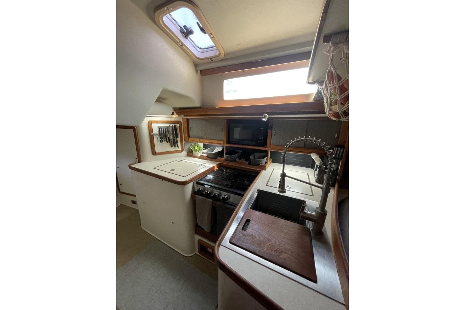 Cozy kitchen in a 1995 Catalina 42 sailboat with modern amenities and natural light.