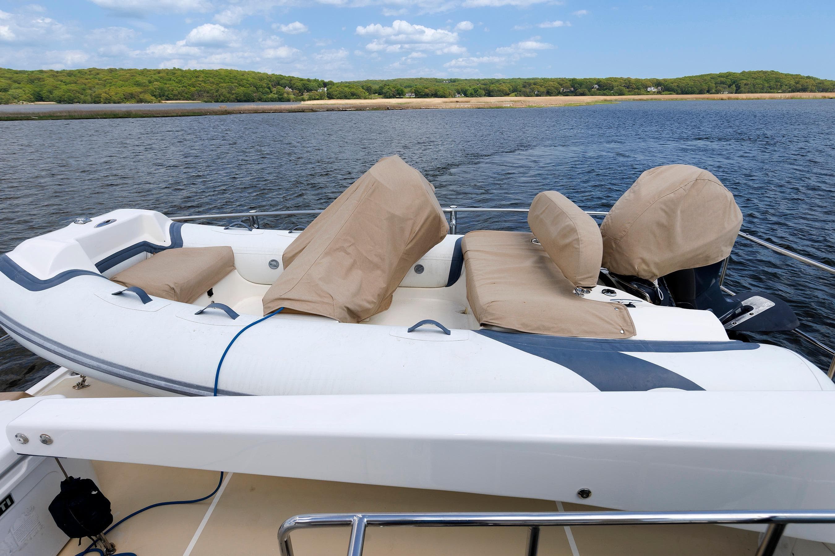Inflatable boat on Grand Banks 59 Aleutian RP yacht, 2007, docked by scenic shoreline.