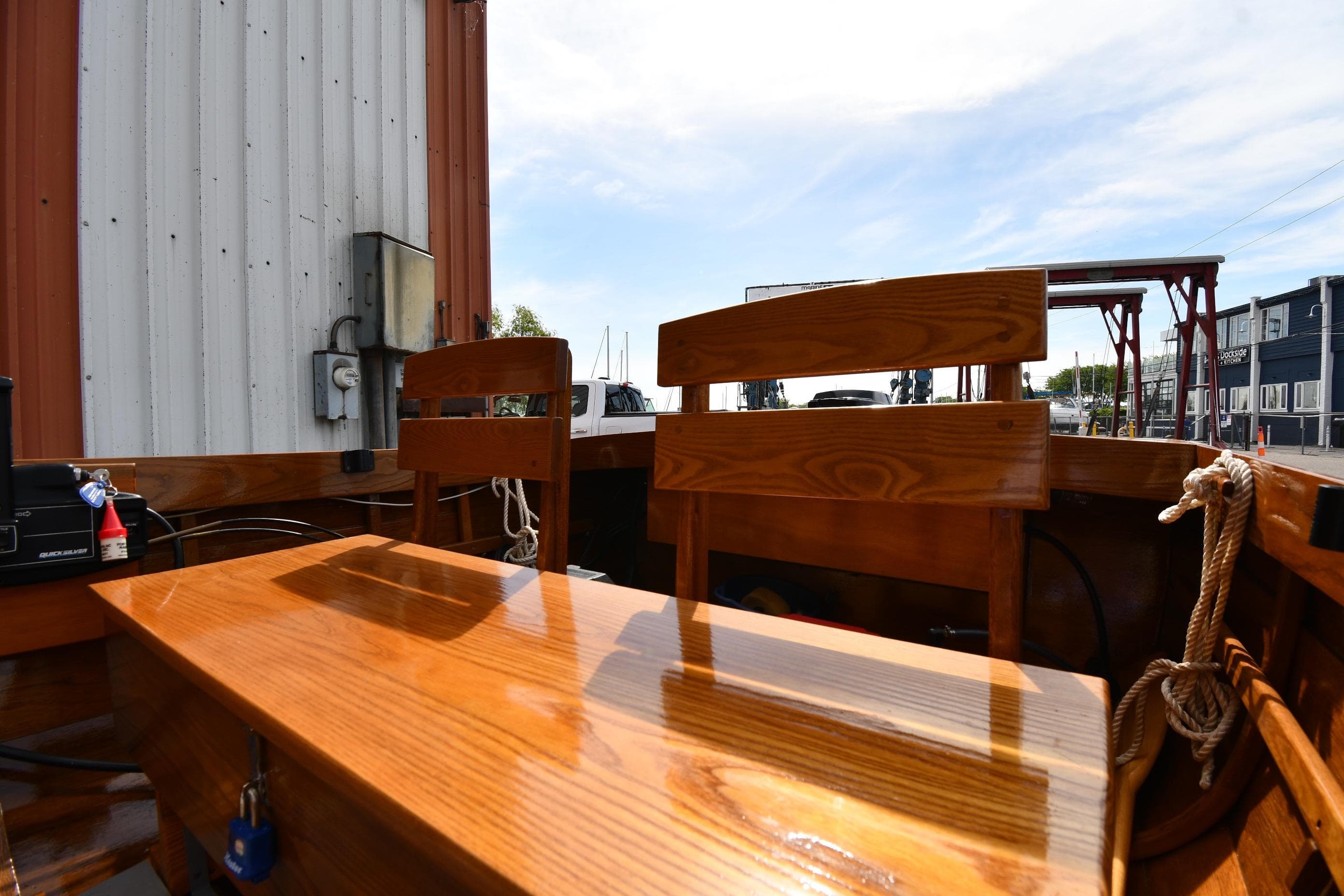 2003 Great Lakes 16 Skiff interior with polished wooden seats and table, dockside view.