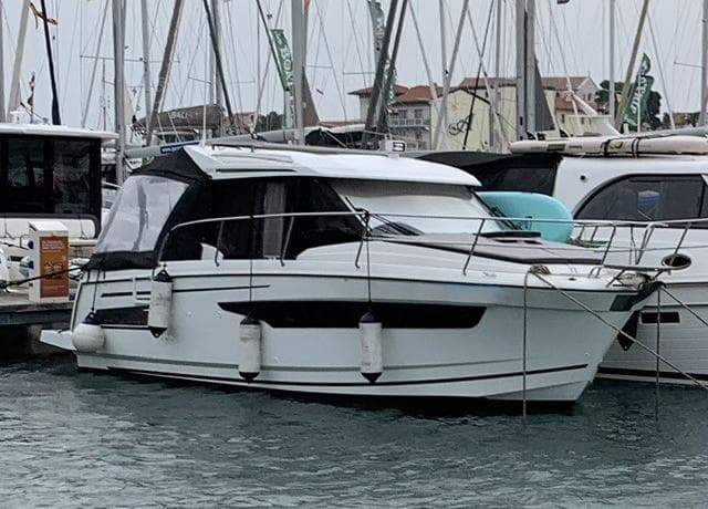 2018 Jeanneau Merry Fisher 895 docked in a marina, surrounded by other boats.