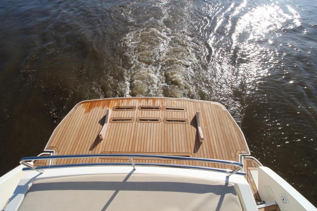 Rear view of 2009 Atlantis 50x4 yacht cruising on water, showcasing wooden deck.