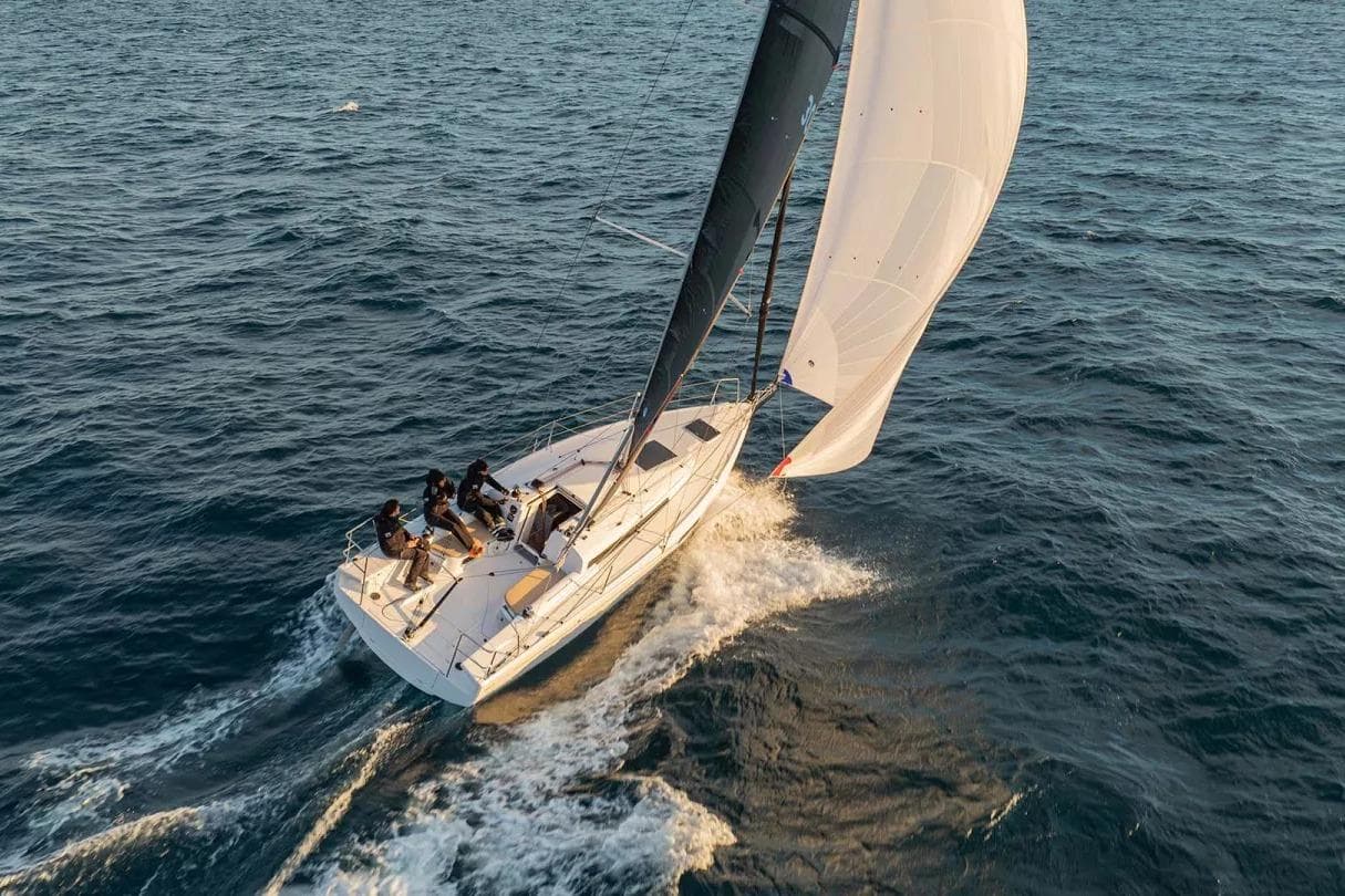 2025 Beneteau First 30 sailboat navigating ocean waters with crew onboard.