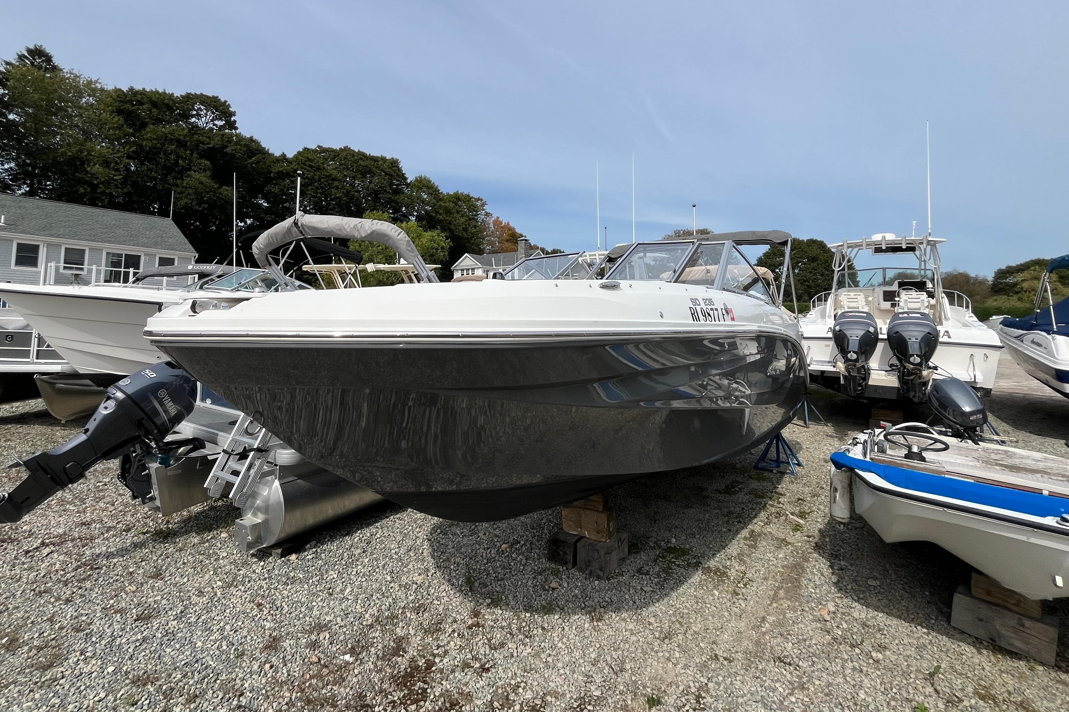 2023 Hurricane SunDeck 235 OB boat on display in a marina setting.