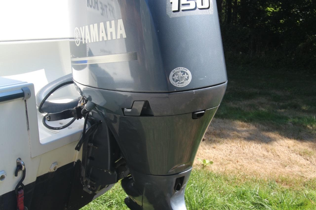 Yamaha 150 outboard motor on 2017 Jeanneau NC Sport 695 boat, parked on grass.