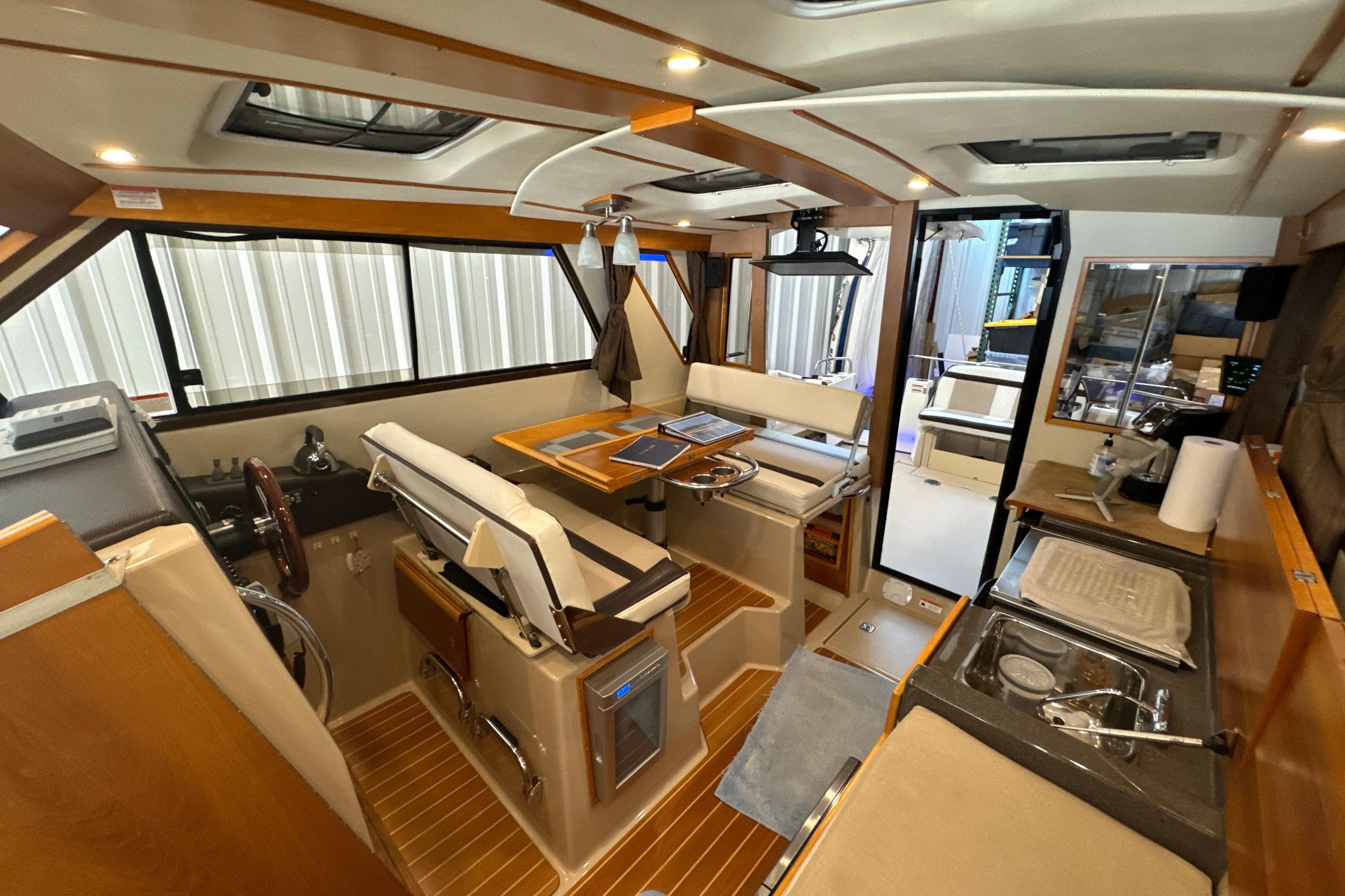 Interior of 2017 Cutwater C-30 Sedan boat, featuring helm, seating, and kitchenette.