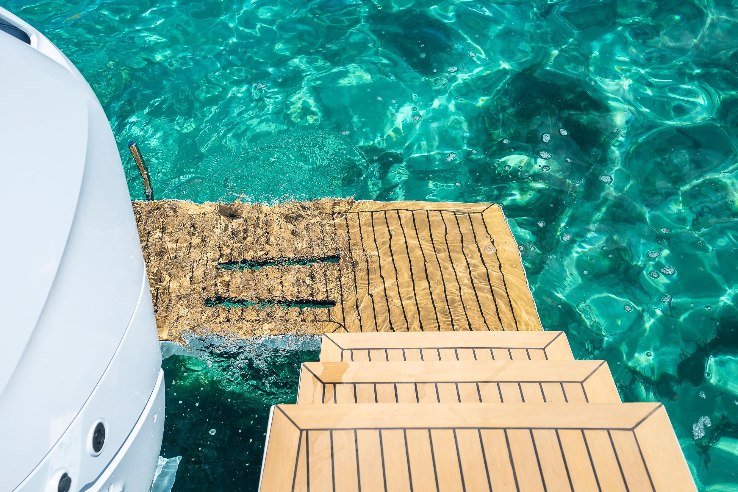 Tesoro T40 Outboard 2025 yacht with wooden steps over clear turquoise water.
