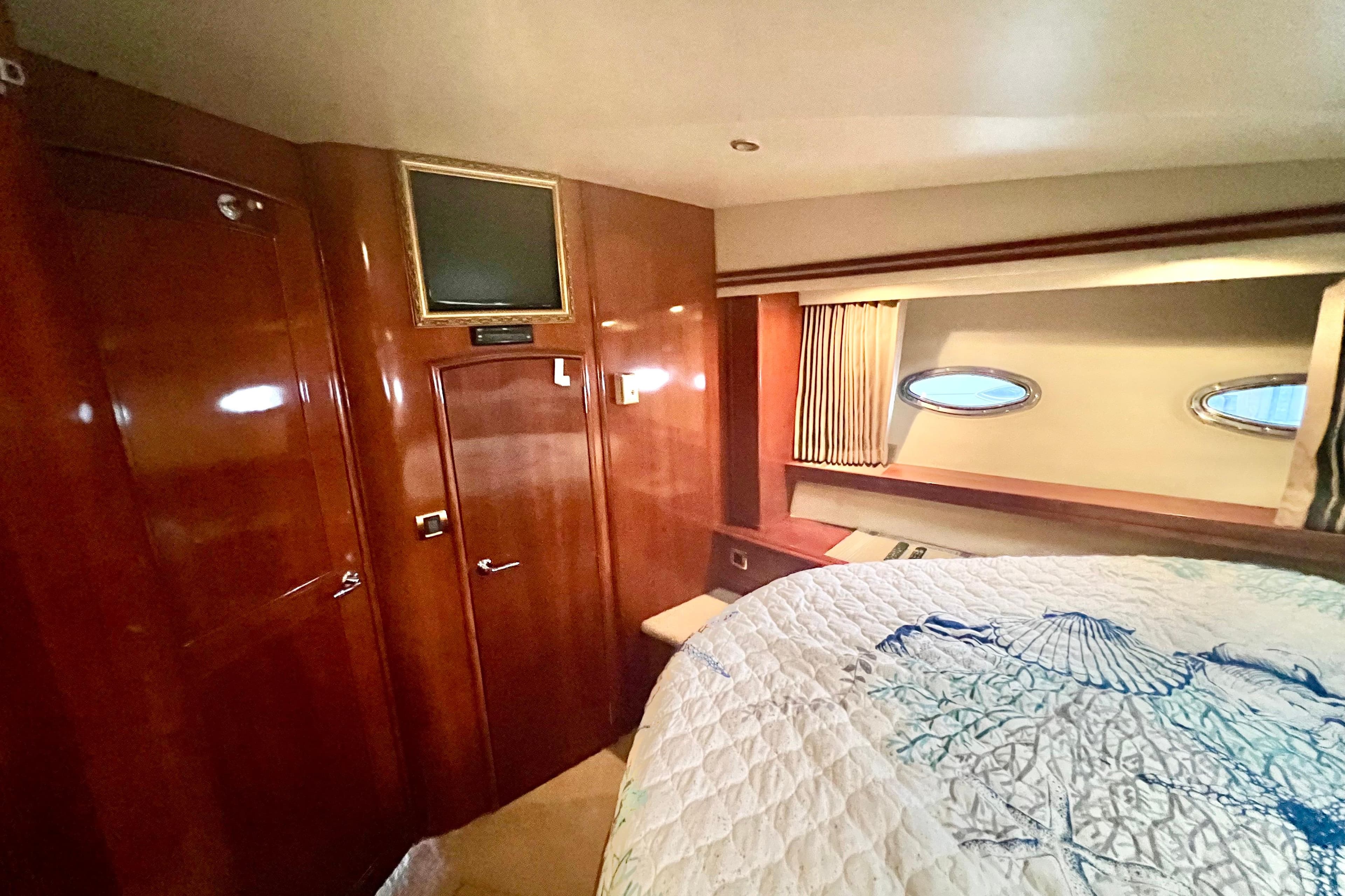 Luxurious 2005 Carver 56 Voyager yacht bedroom with elegant wood paneling and cozy bedding.